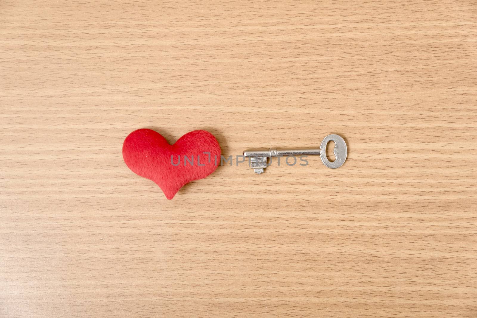 red heart with key on wood table background