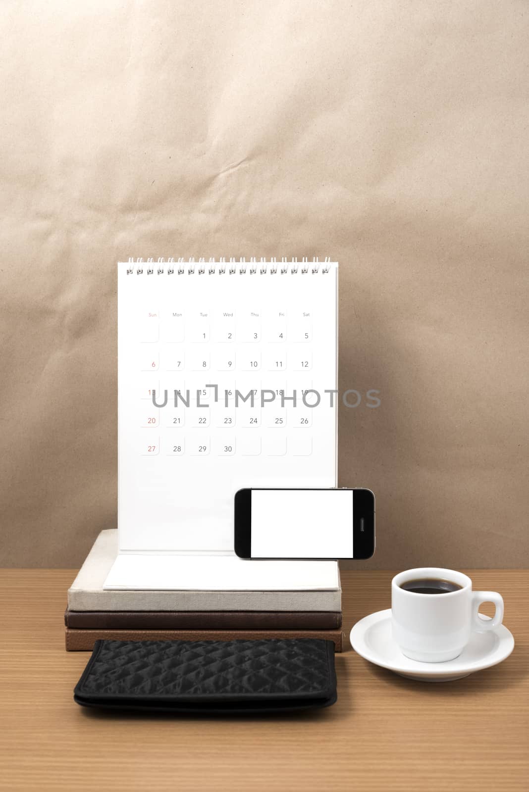 working table : coffee with phone,stack of book and wallet on wood background