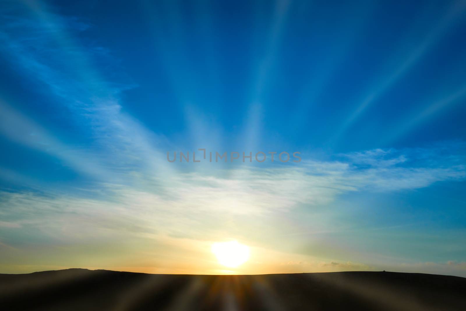 Sun rising above the land on blue sky. Nature background with sunny beams