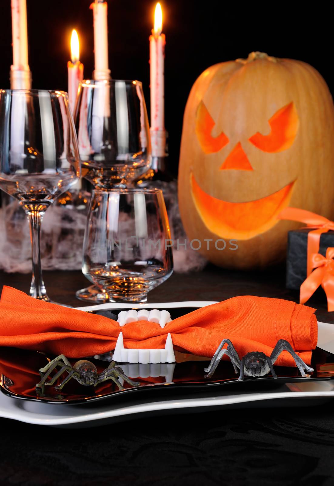 Napkin clamped in his teeth on a plate with spiders Halloween table