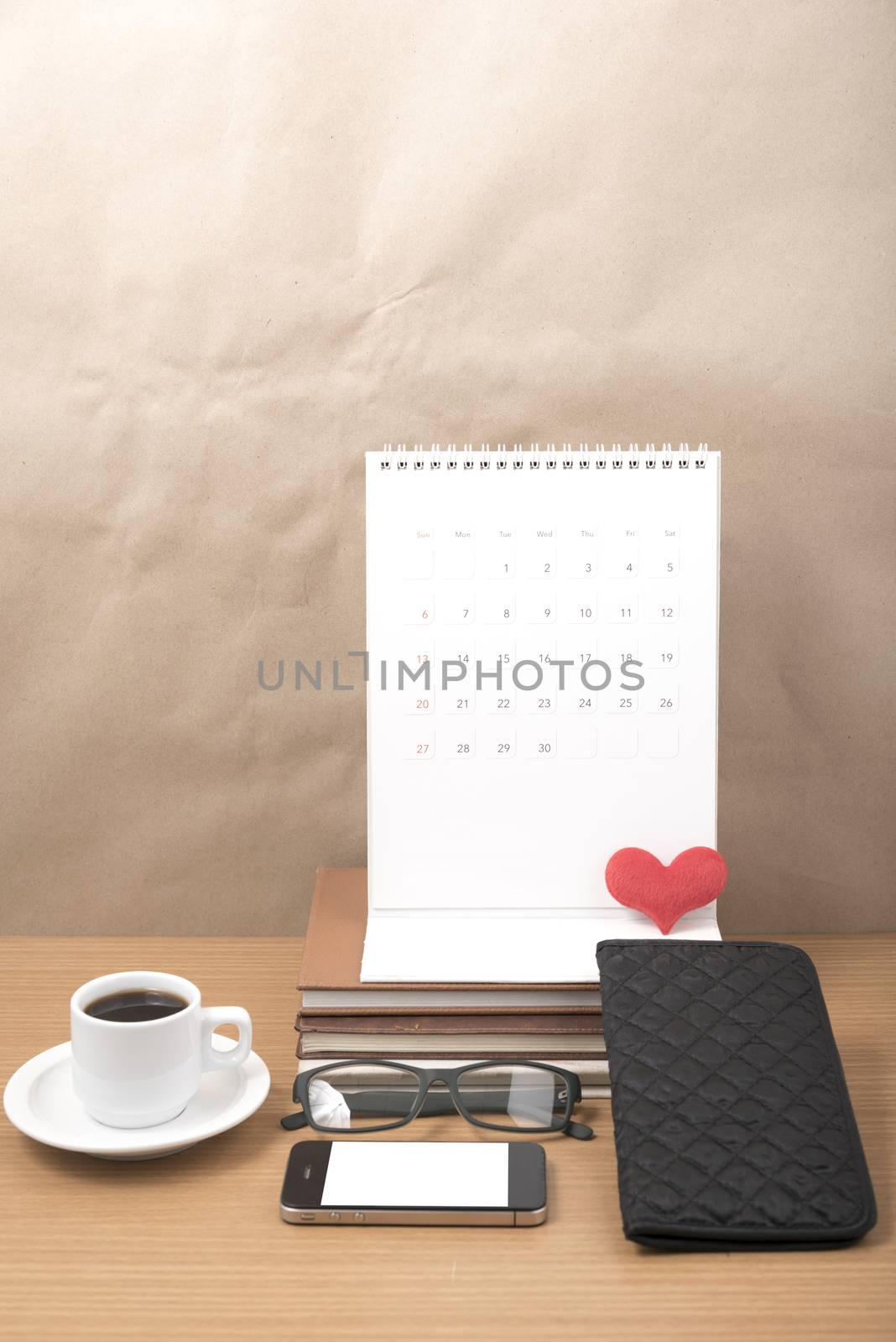 office desk : coffee with phone,stack of book,eyeglasses,wallet,calendar,heart on wood background