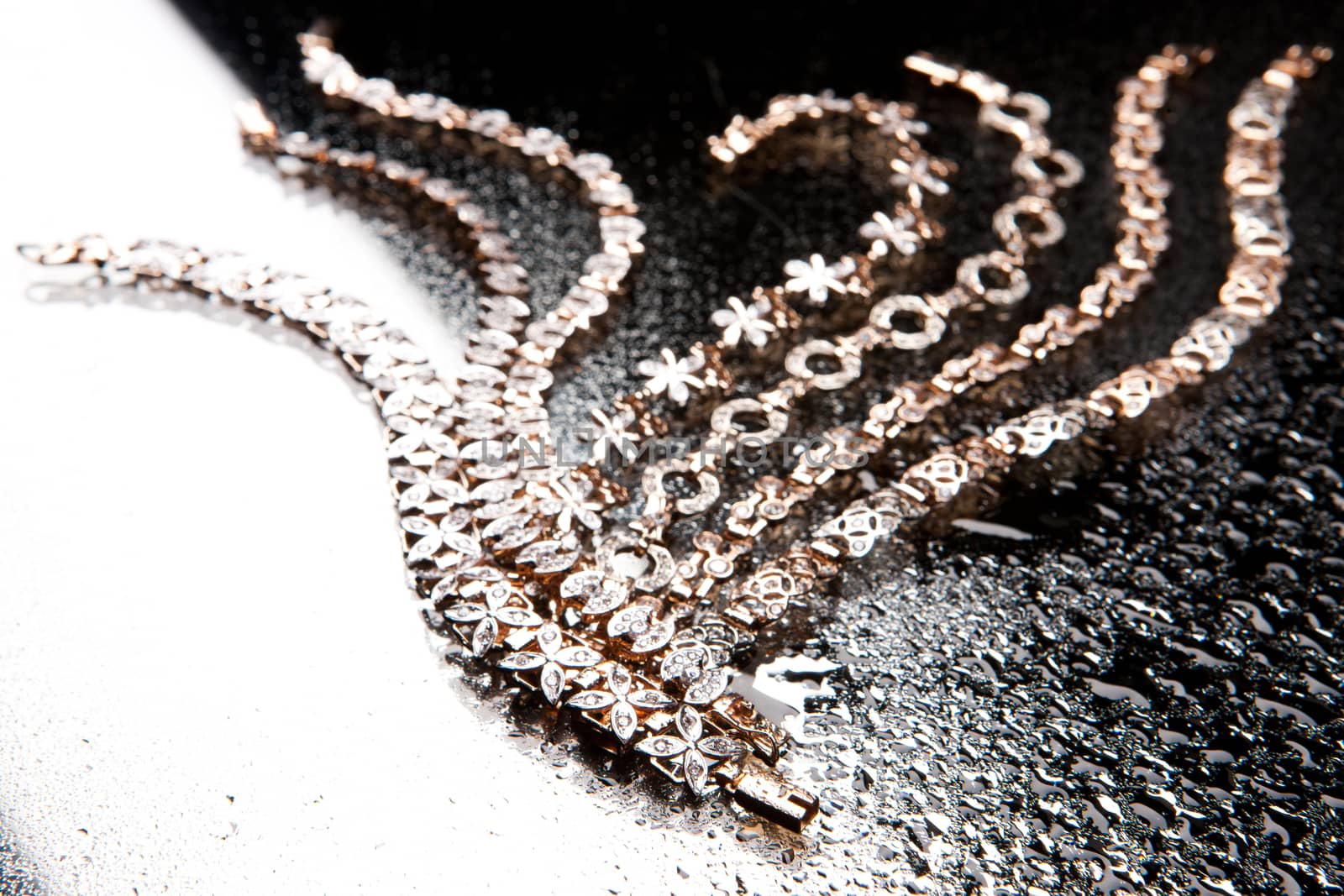 Golden bracelets on a black glass background with white highlight
