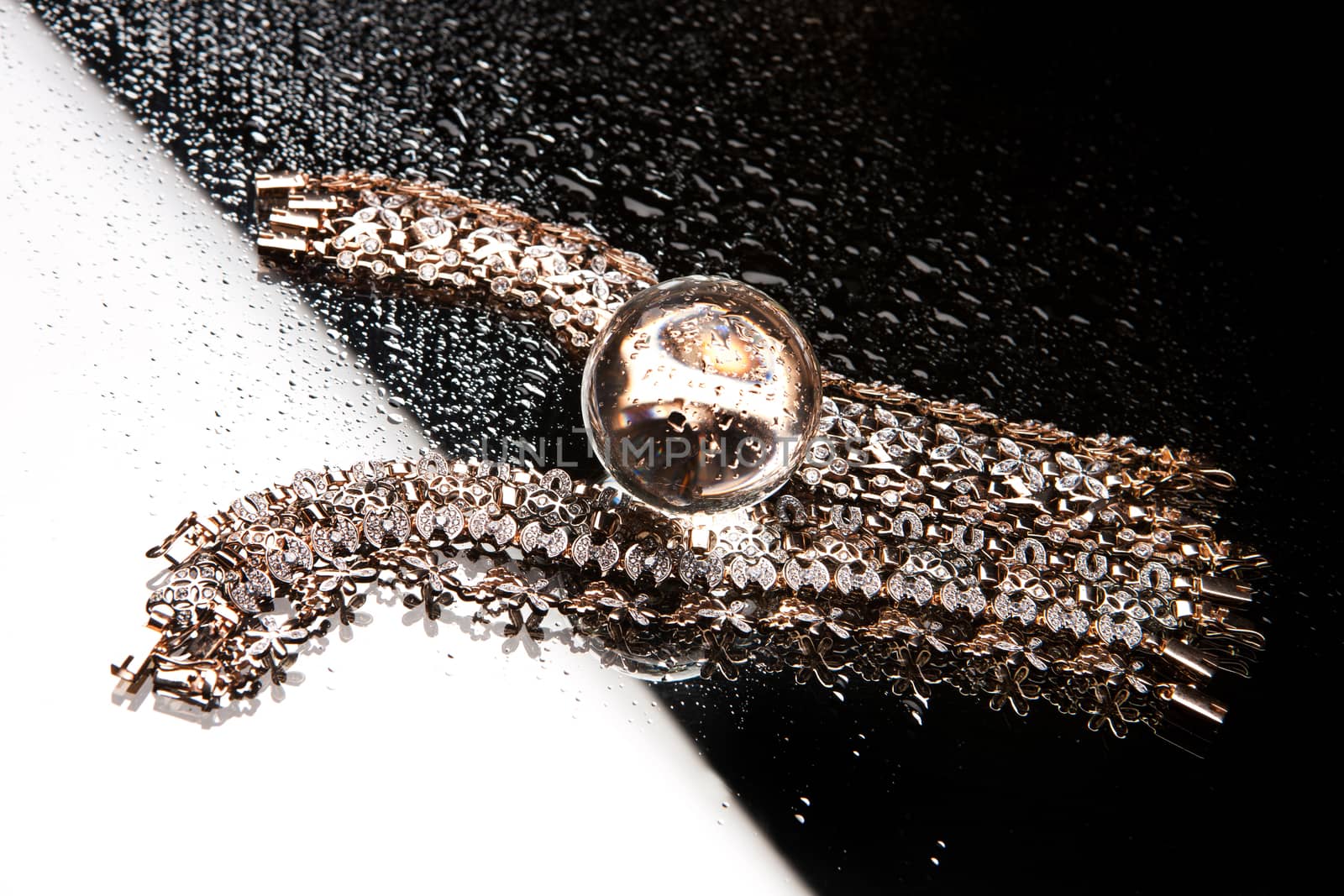 Golden bracelets on a black glass background with white highlight