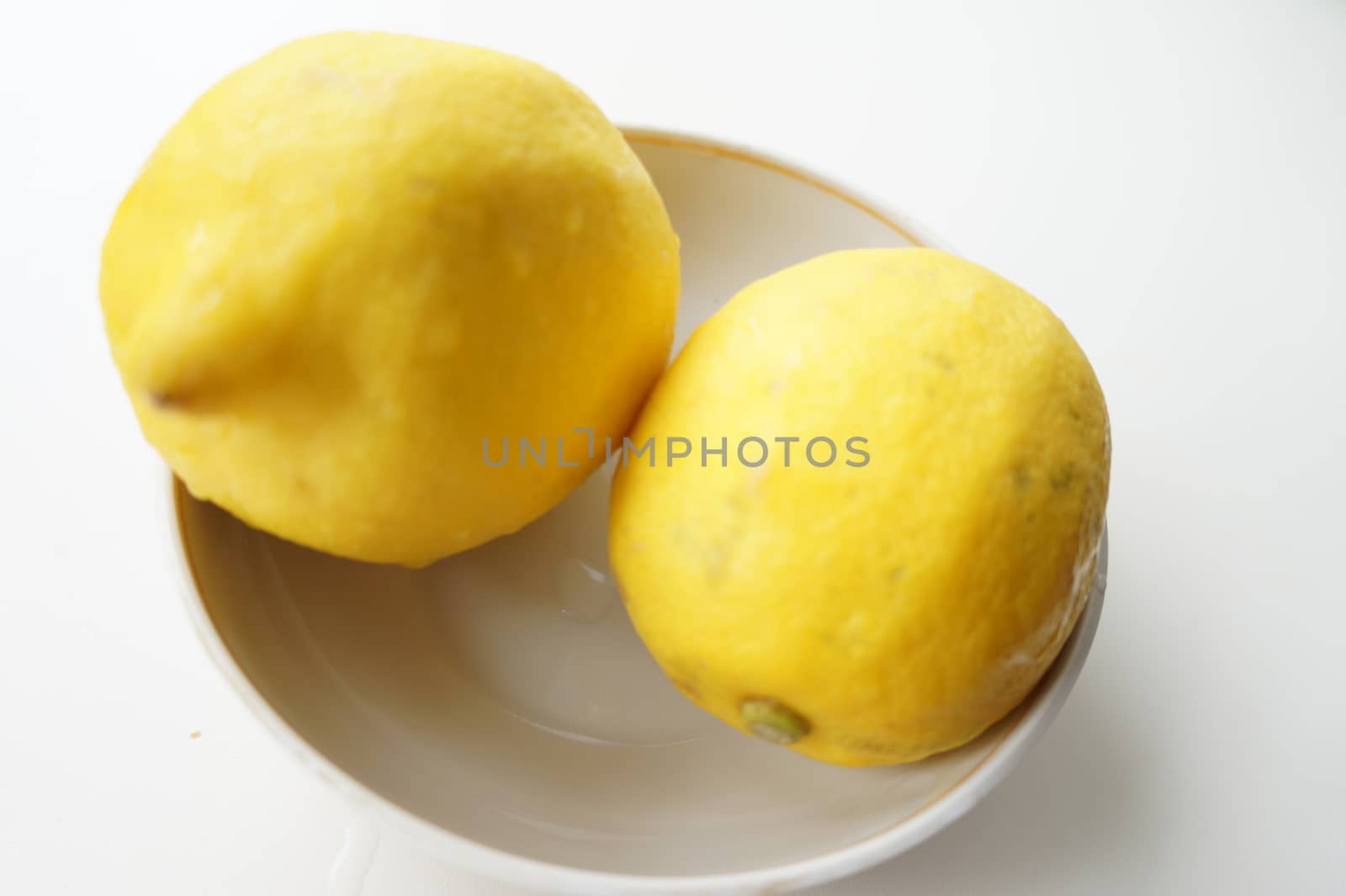 Yellow ripe lemons on a small white saucer