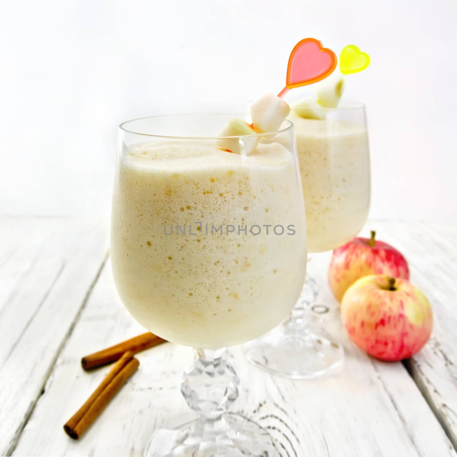 Jelly airy apple in wineglasses, red apples and cinnamon on a background of bright wooden boards