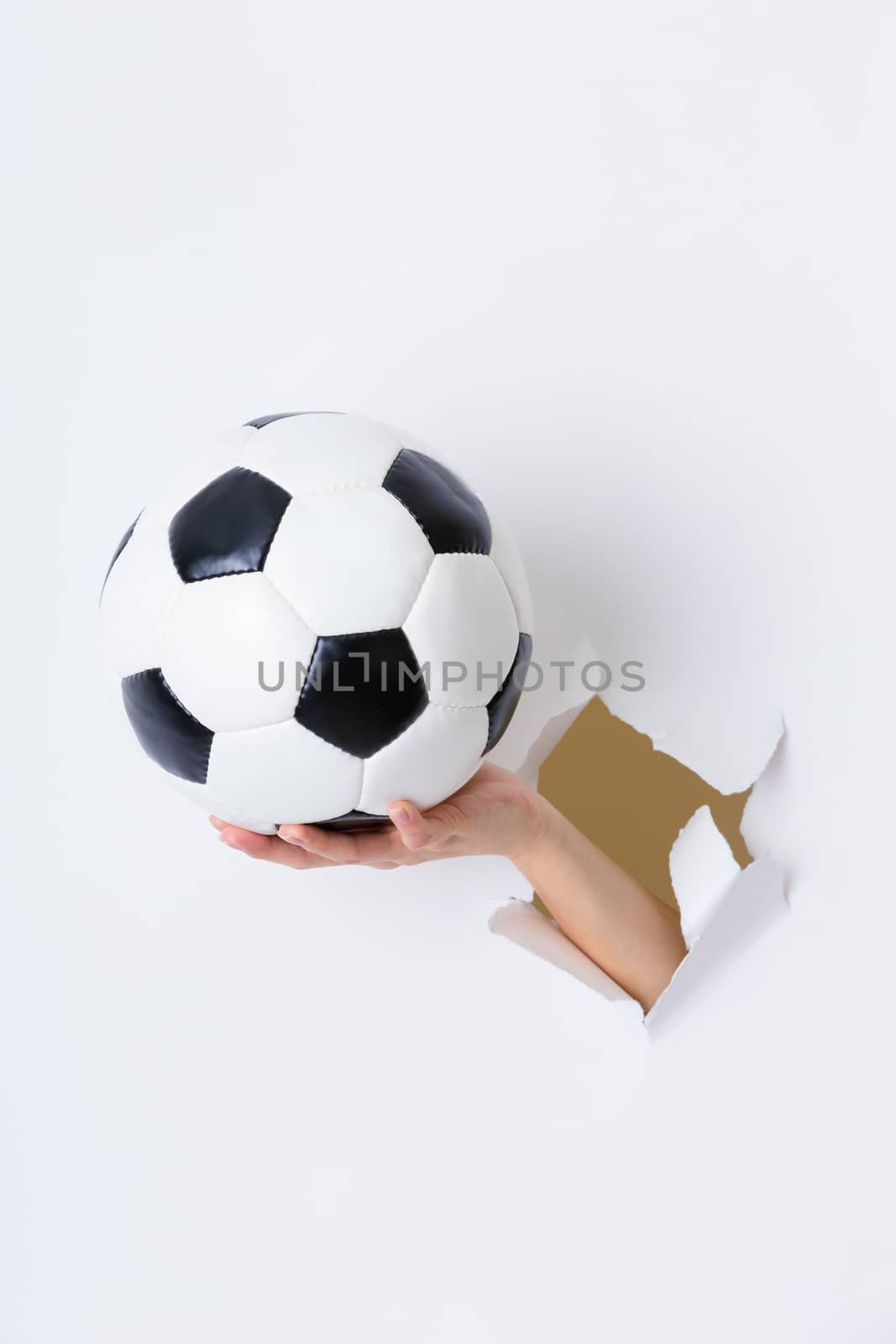 Hand through the hole in paper with soccer ball