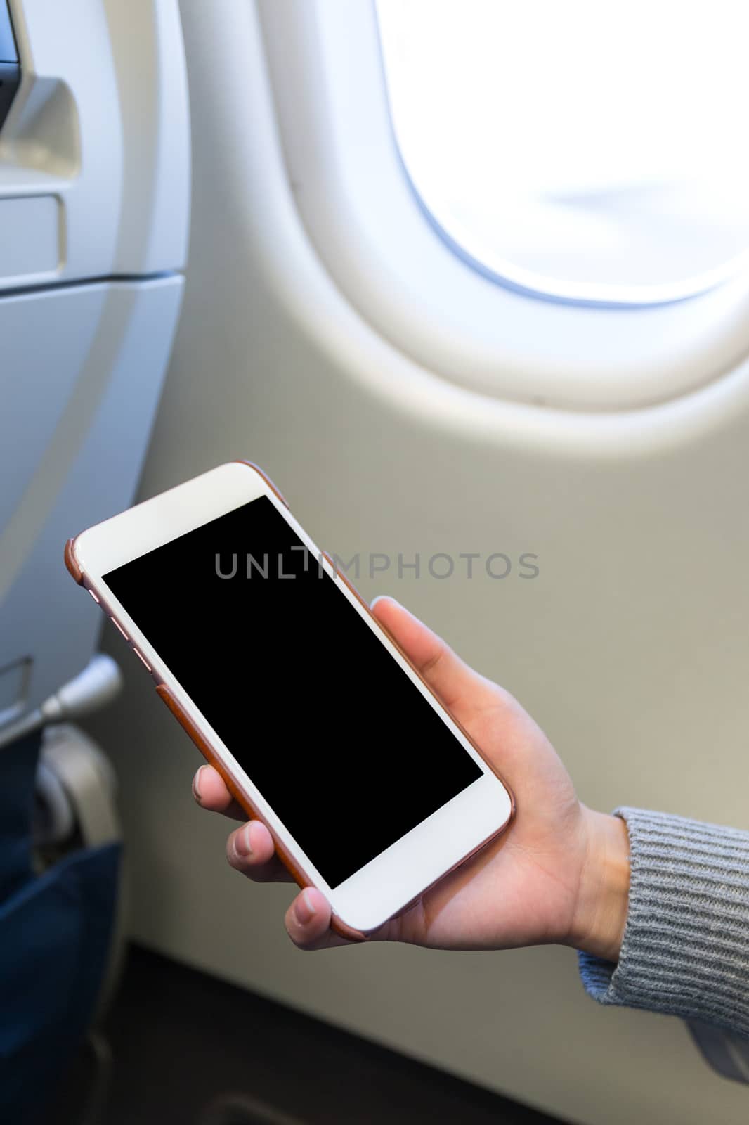 Woman holding digital mobile phone at airplane by leungchopan