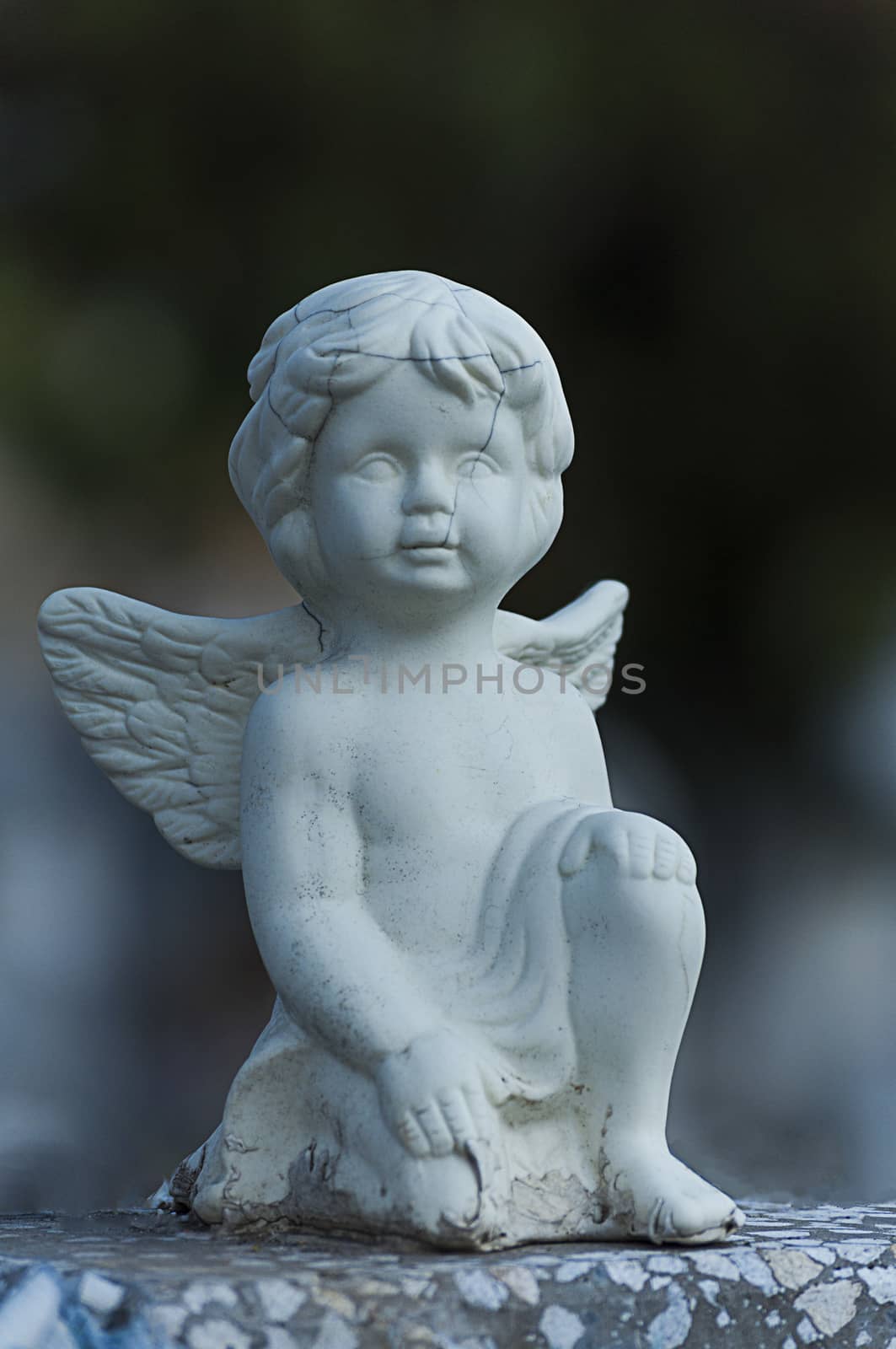 Angel watching over a tombstone. Cemetery figurine. Aged marble