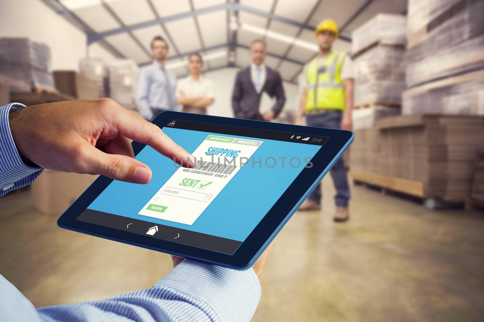 Man using tablet pc  against warehouse team standing looking at camera