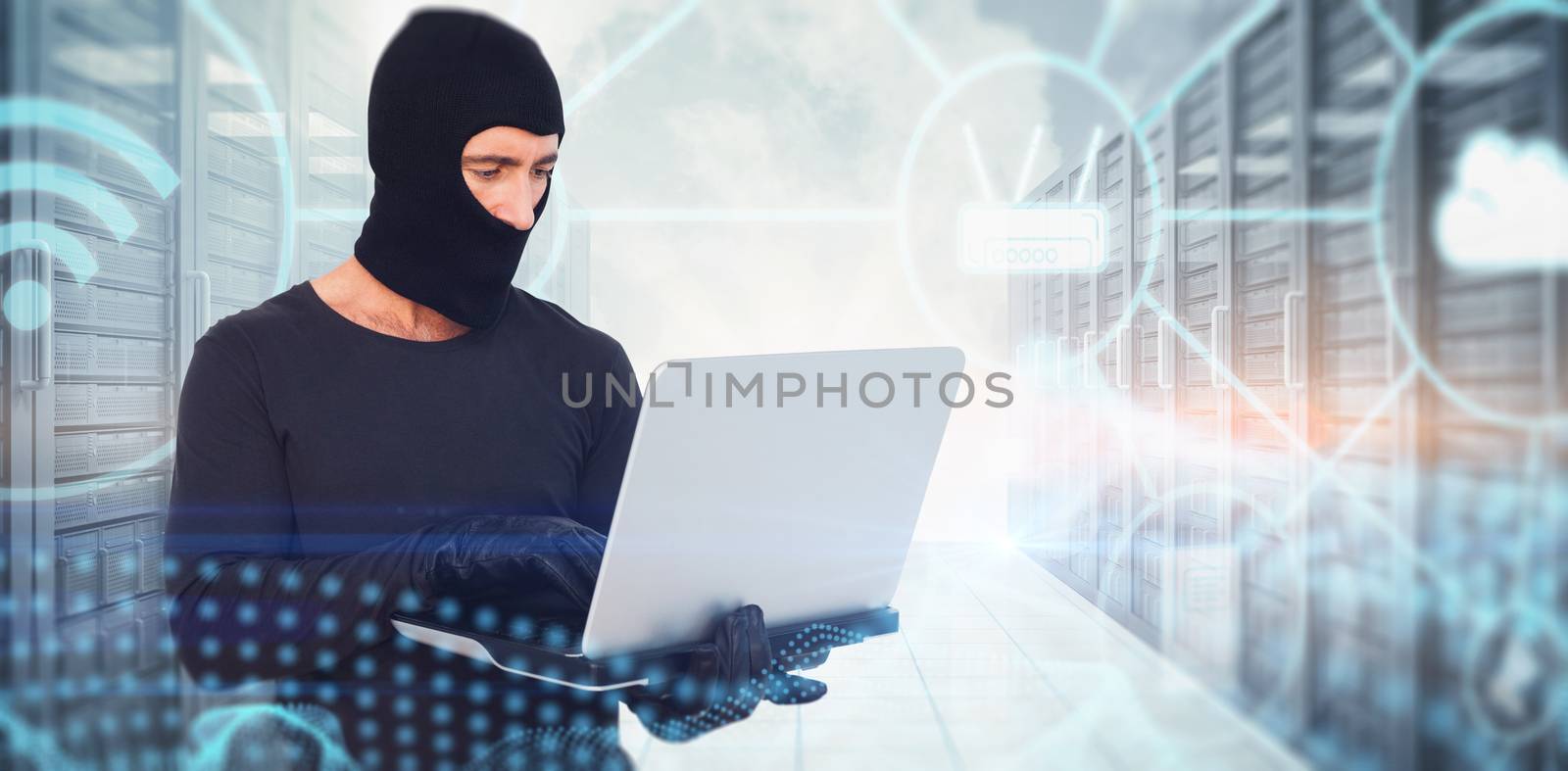Burglar with balaclava hacking a laptop against abstract glowing black background