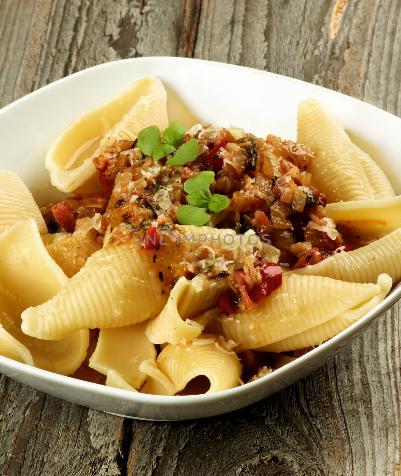 Delicious Conchiglie Giganti Pasta (Giant Pasta Shells) with Meat Sauce Bolognese in White Bowl Cross Section on Wooden background