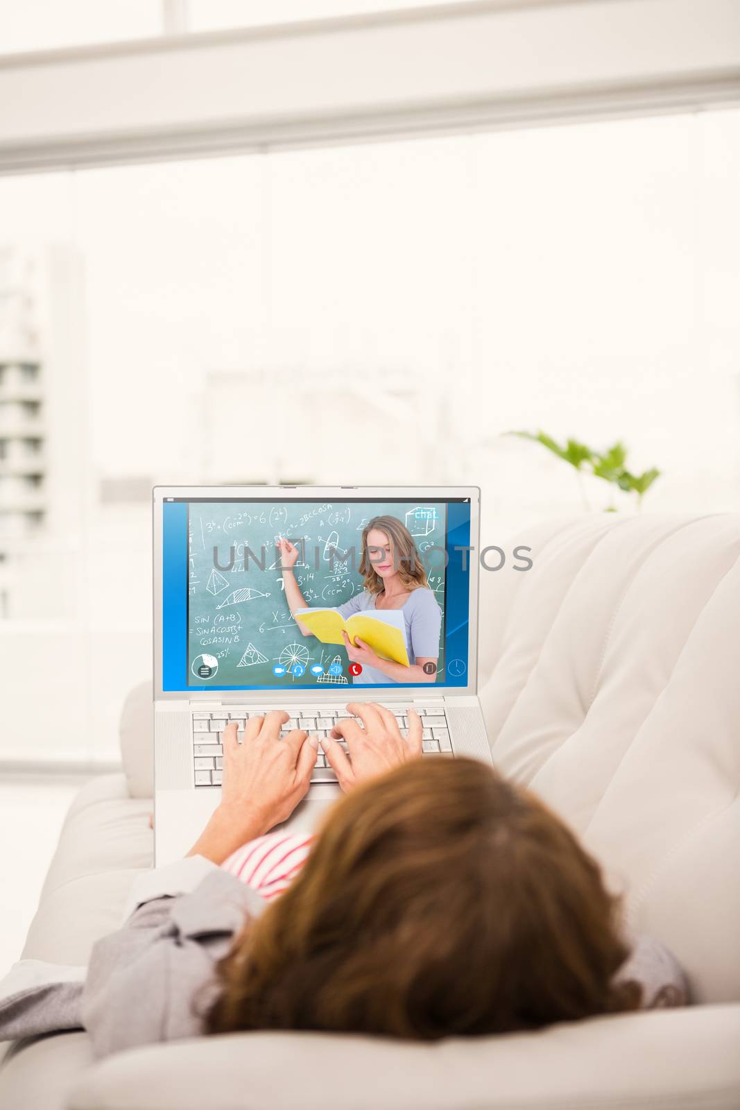 Teacher reading book while writing on blackboard against woman using laptop while relaxing on sofa