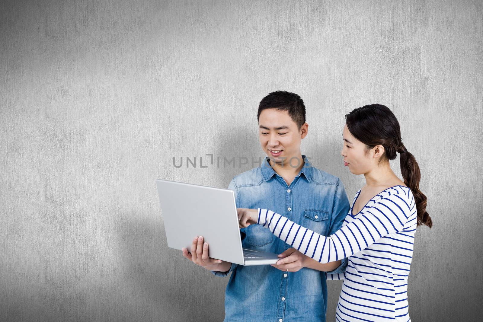 Couple using laptop against white and grey background