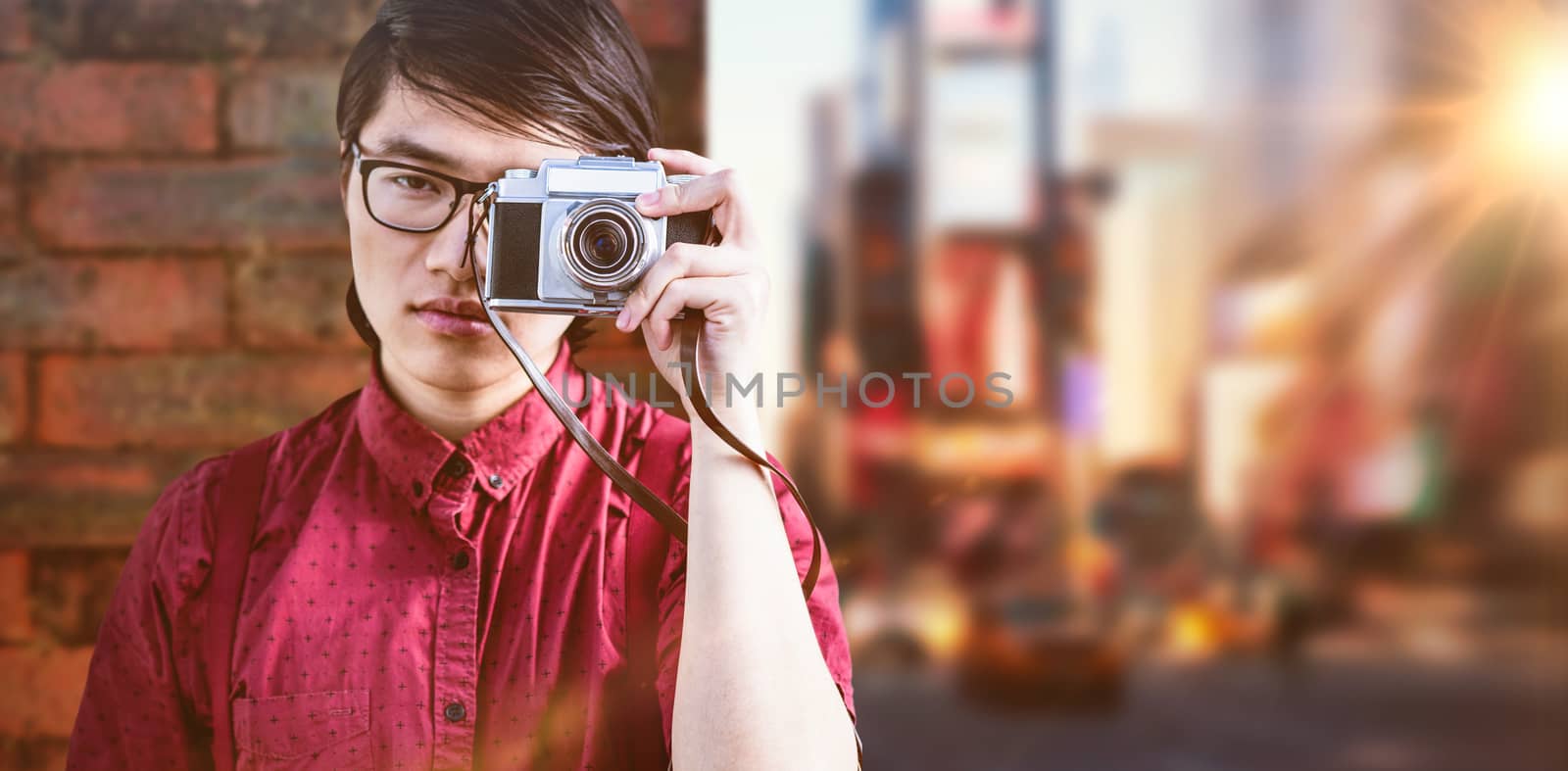 Hipster taking pictures with an old camera against wall of a house