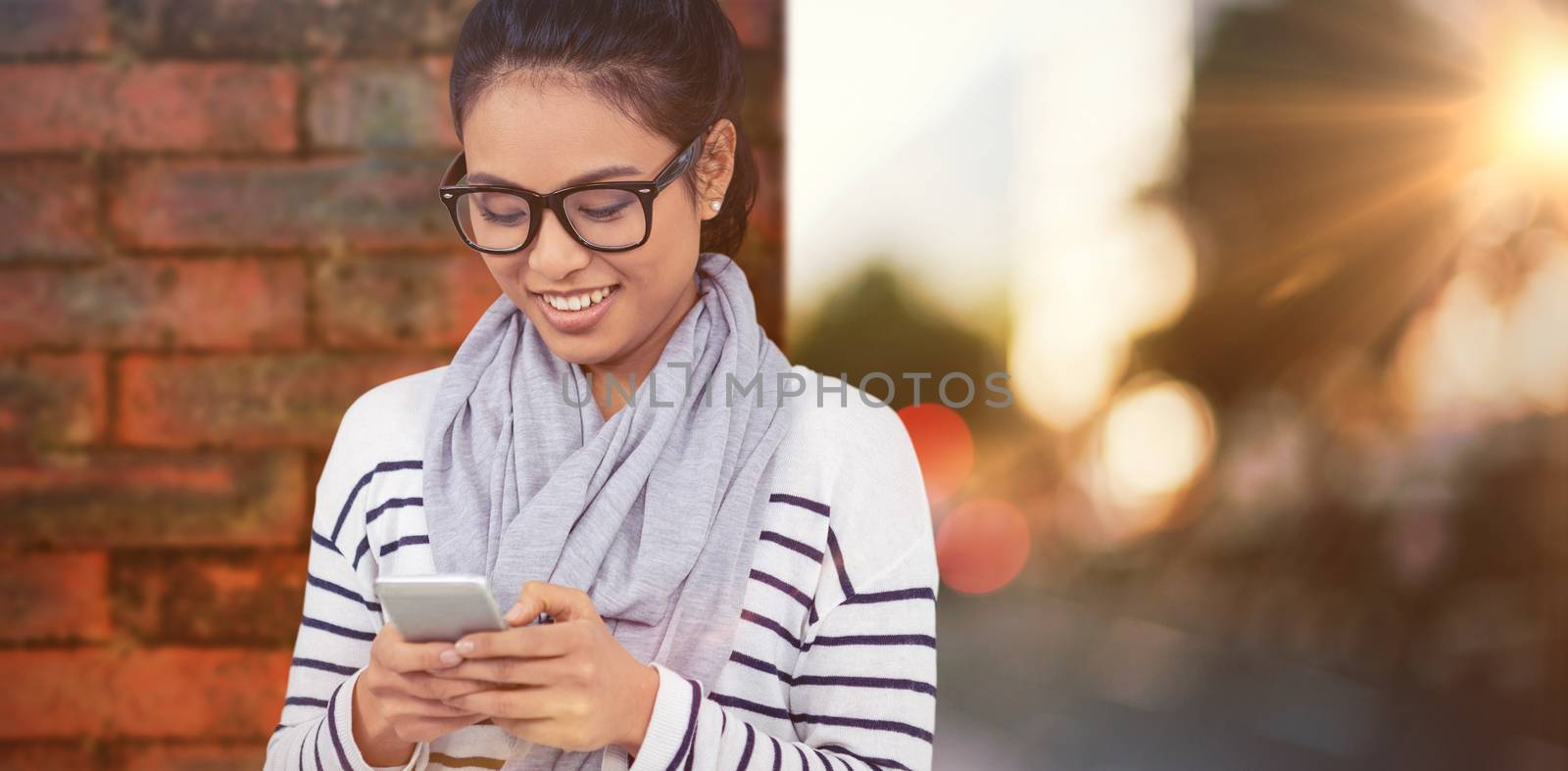 Smiling Asian woman using smartphone against wall of a house
