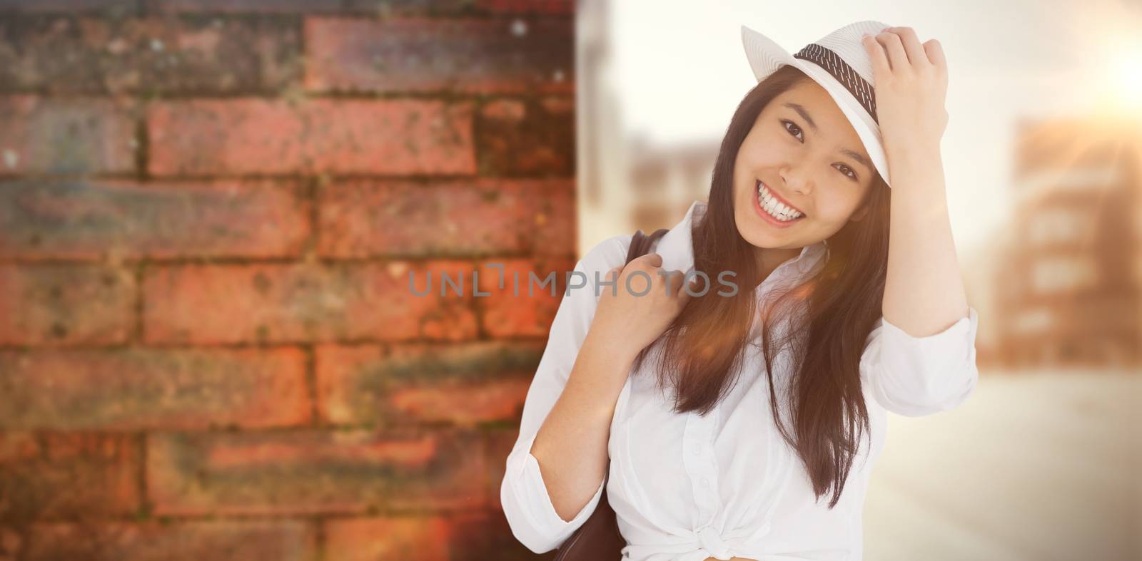 Woman with casual clothes holding her hat against wall of a house