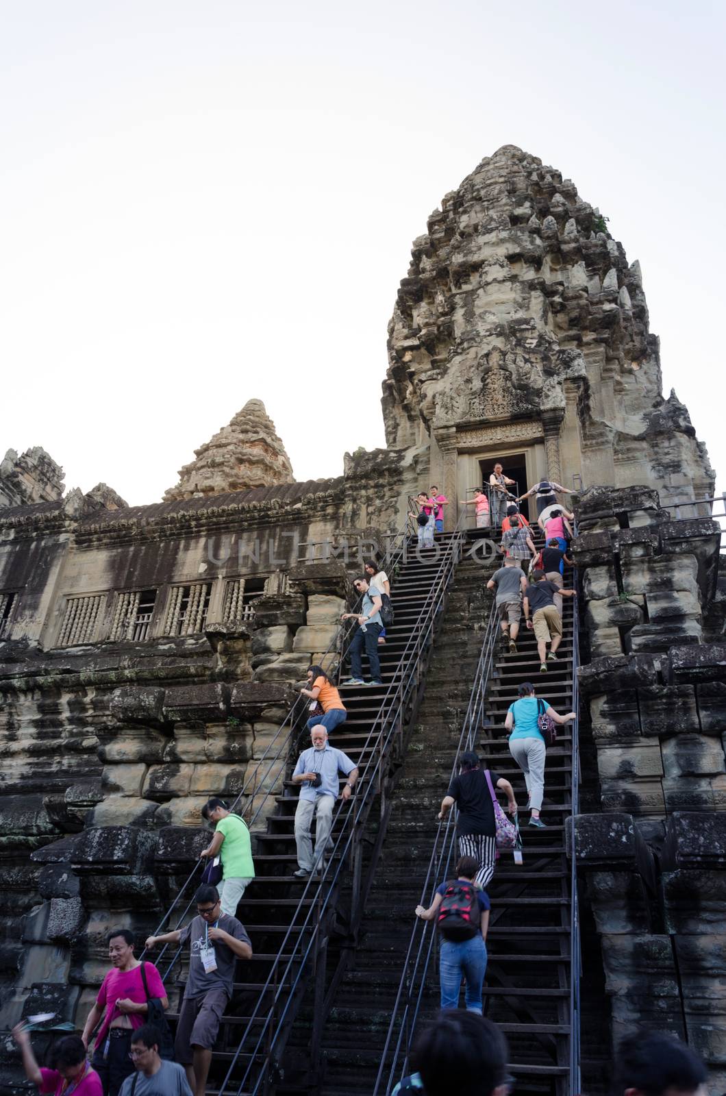 Siem Reap, Cambodia - December 4, 2015: Tourists climb to a praying tower at Angkor Wat. by siraanamwong