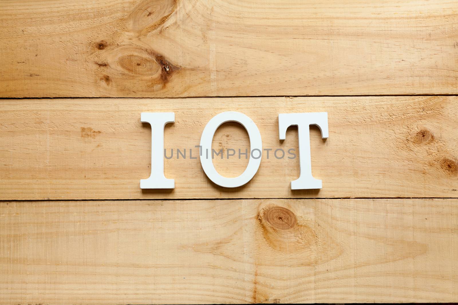 White letters representing the acronym of the Internet of things concept on wooden background