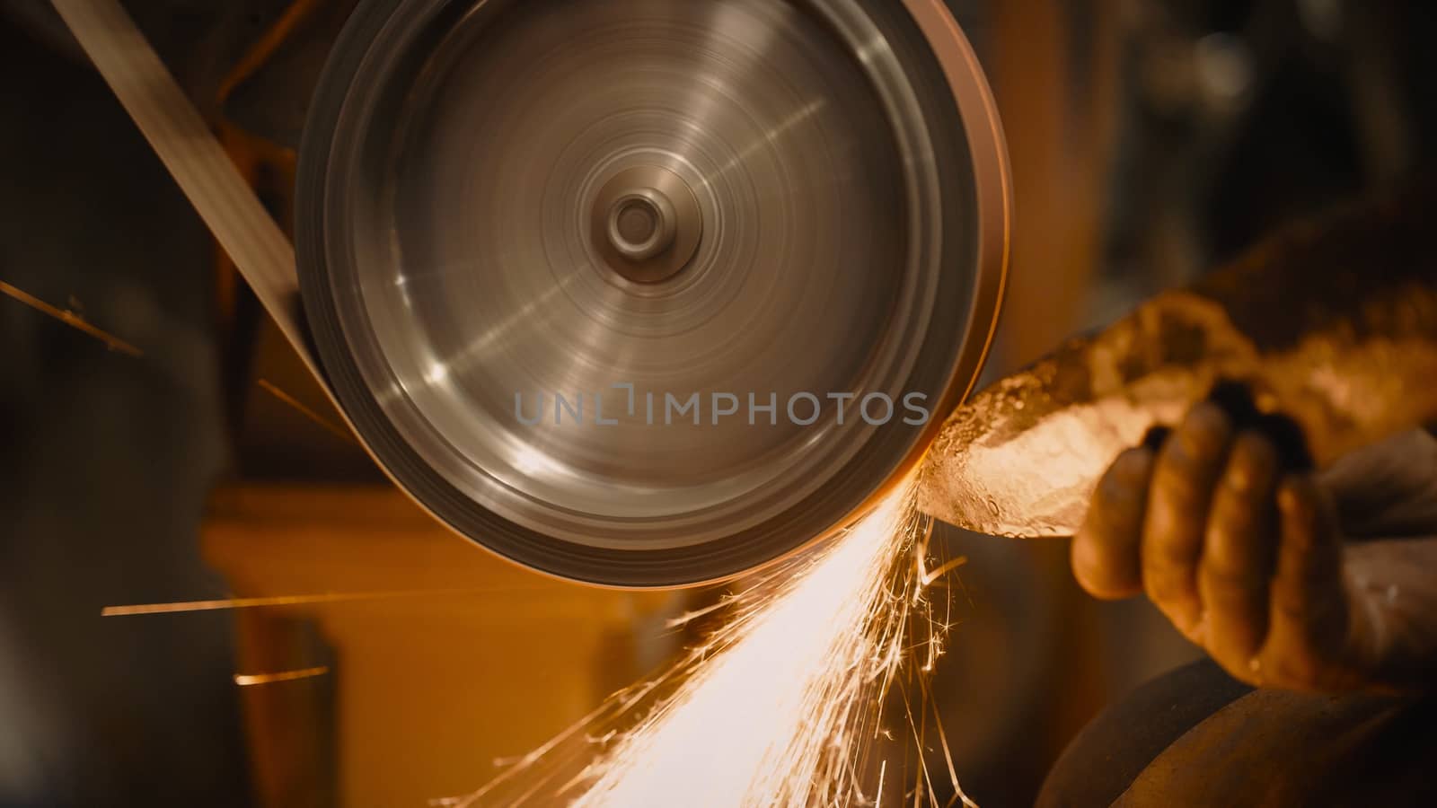 Craftsman uses a belt sander in a mechanical workshop.