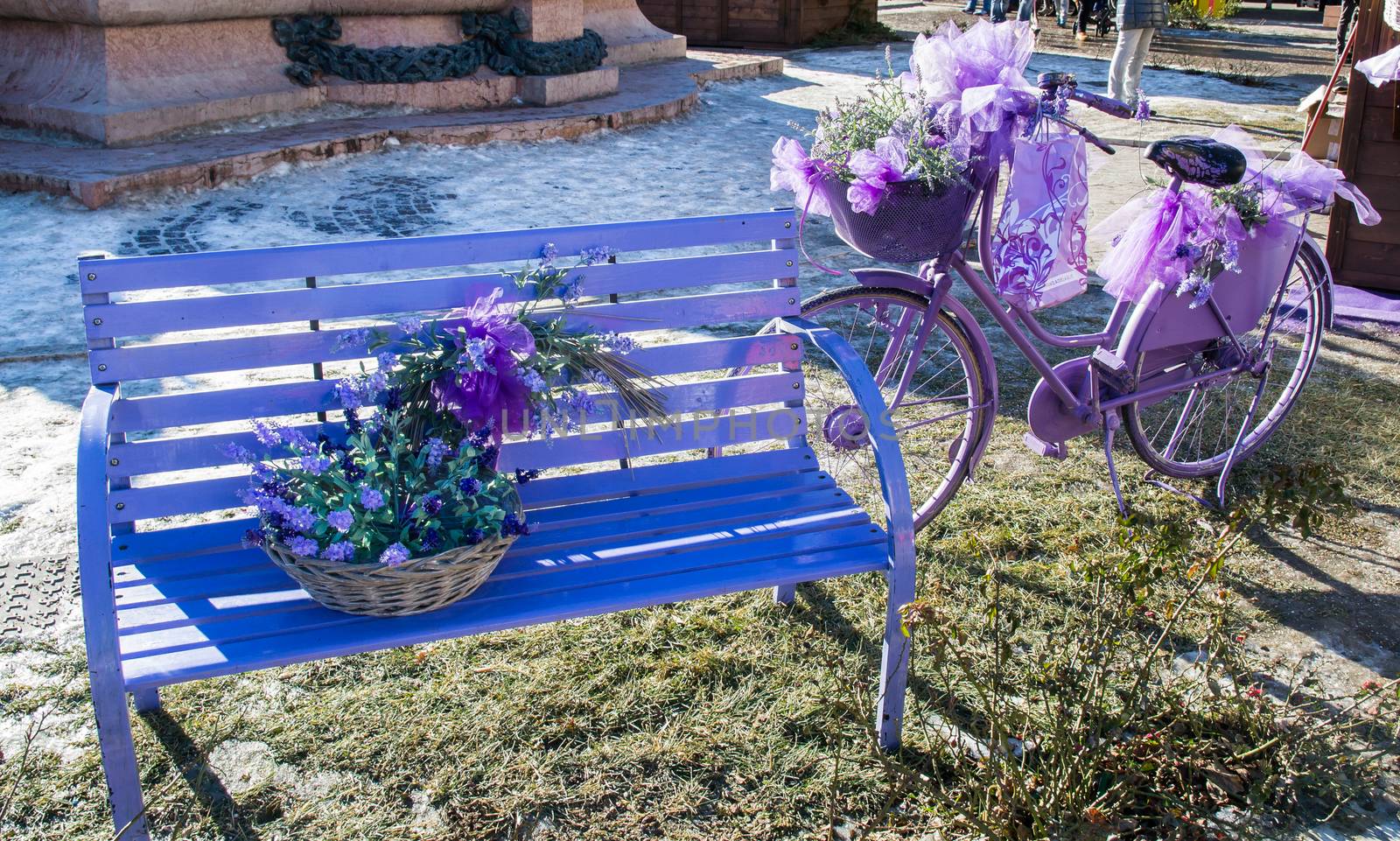 Wooden bench and old bicycle painted in purple and decorated with flowers and matching accessories.