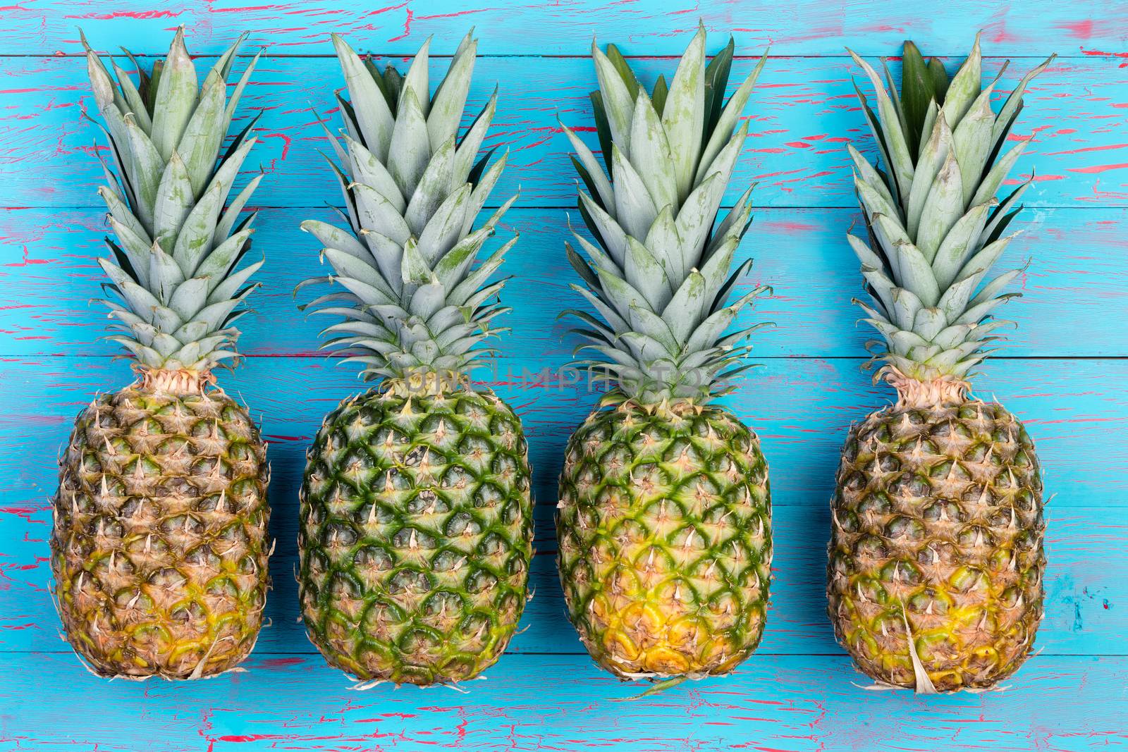 Four pineapples beside each other on table by coskun