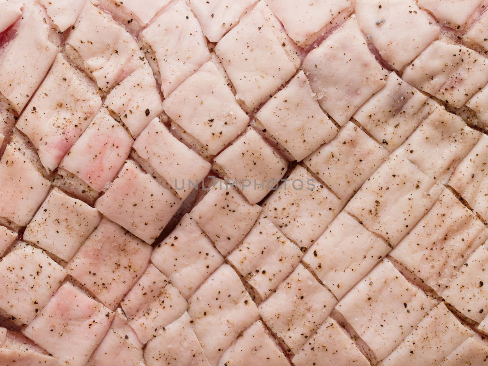 close up of raw uncooked seasoned scored pork belly skin background