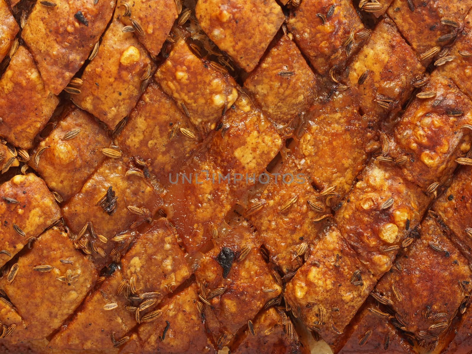 close up of rustic scored golden roasted pork belly skin background