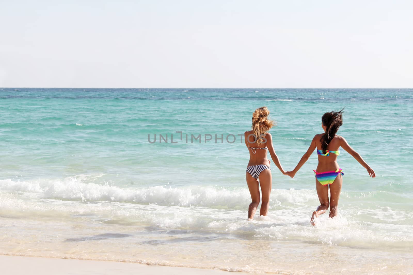 Beautiful fit women in bikni run to tropical sea