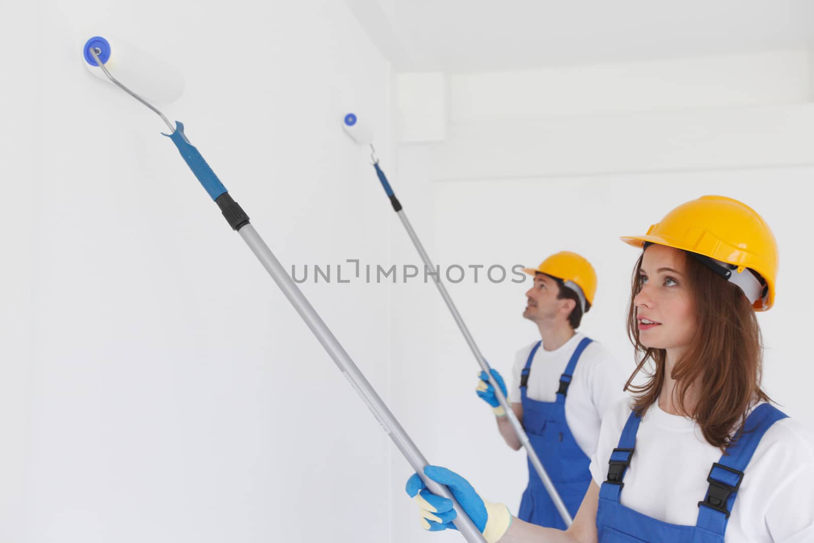 Team of young workers in hardhats painting the wall