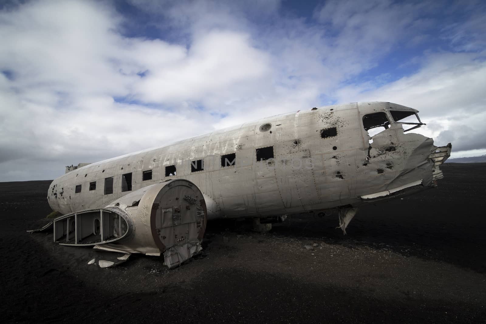 Horizontal side view of a plane wreck on black sands and background of blue sky in south of Iceland