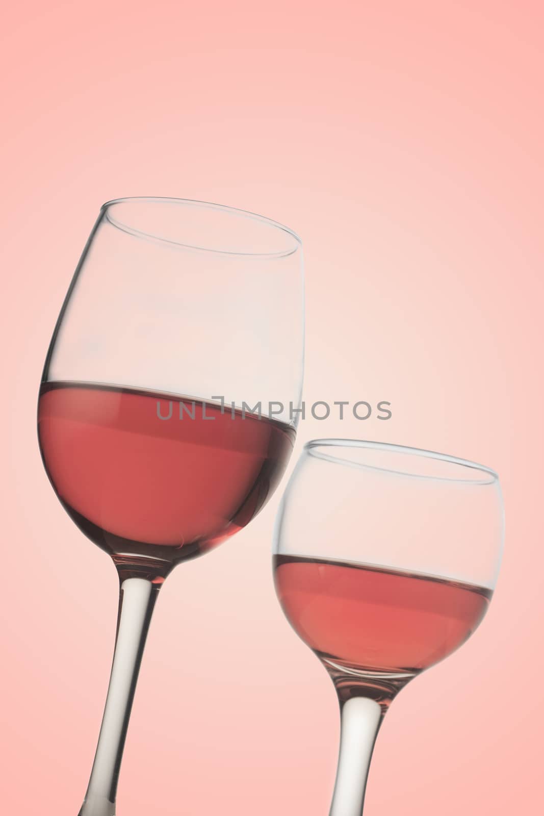 Vertical front view of two rose wine glasses isolated on pink background