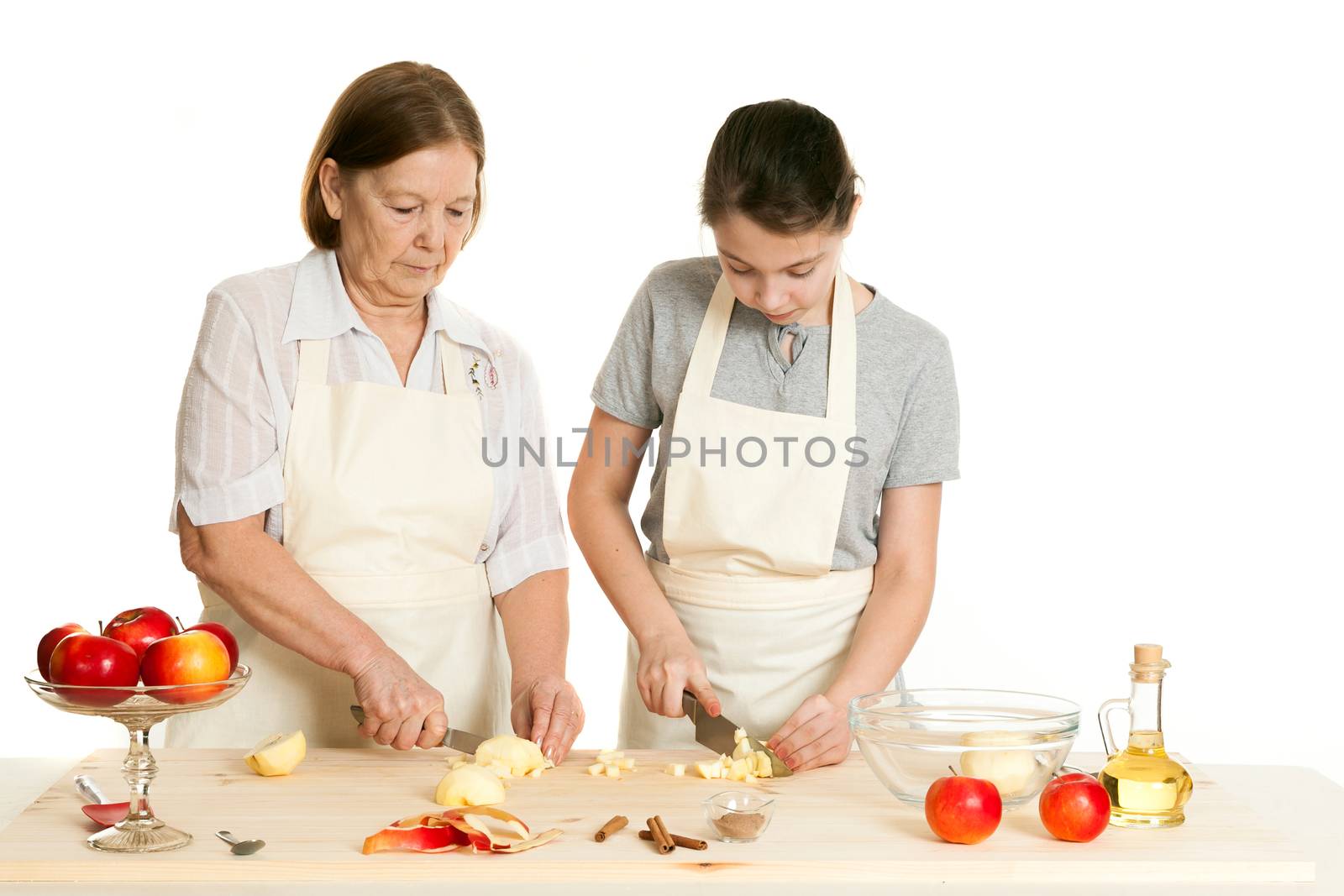 the grandmother teaches the granddaughter to knife apples on a white background