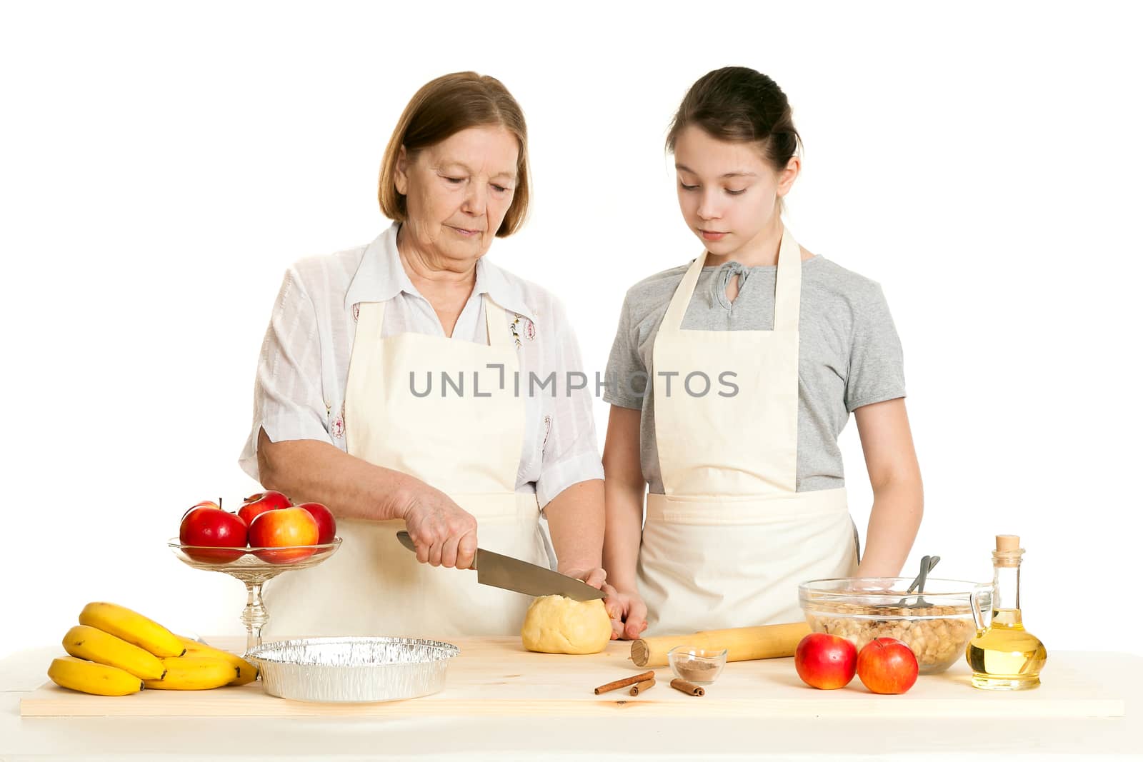 the grandmother and the granddaughter cut dough on a table  by sveter
