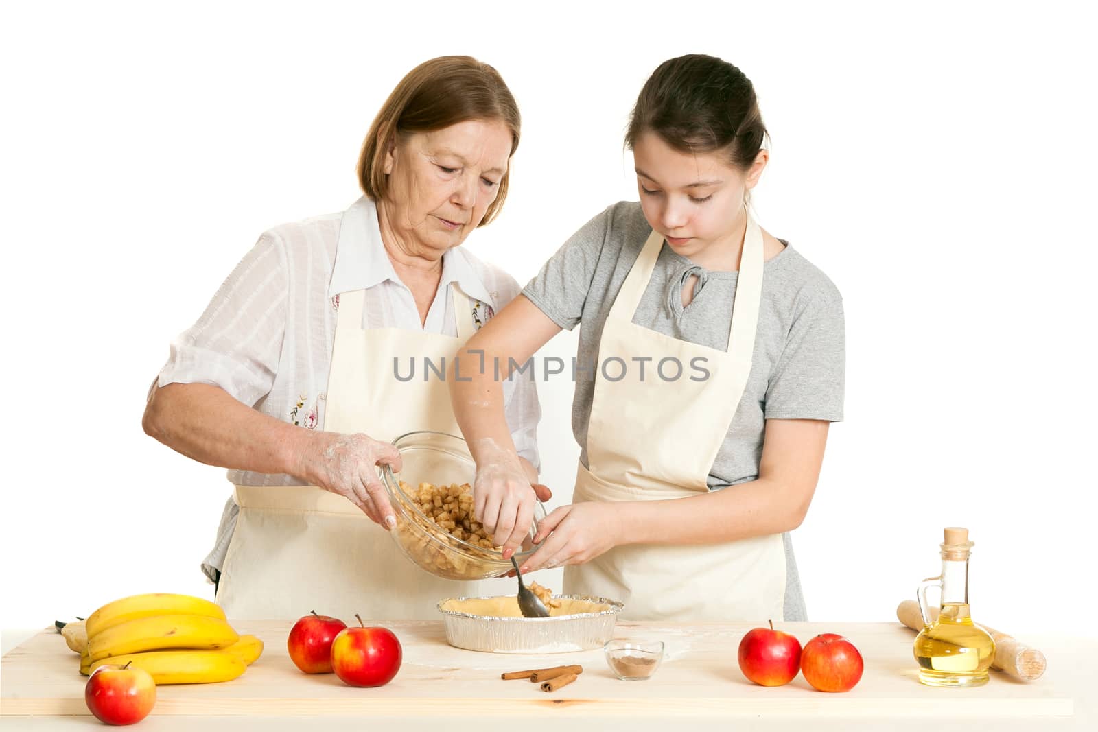 the grandmother and the granddaughter stack a stuffing in a form for pie