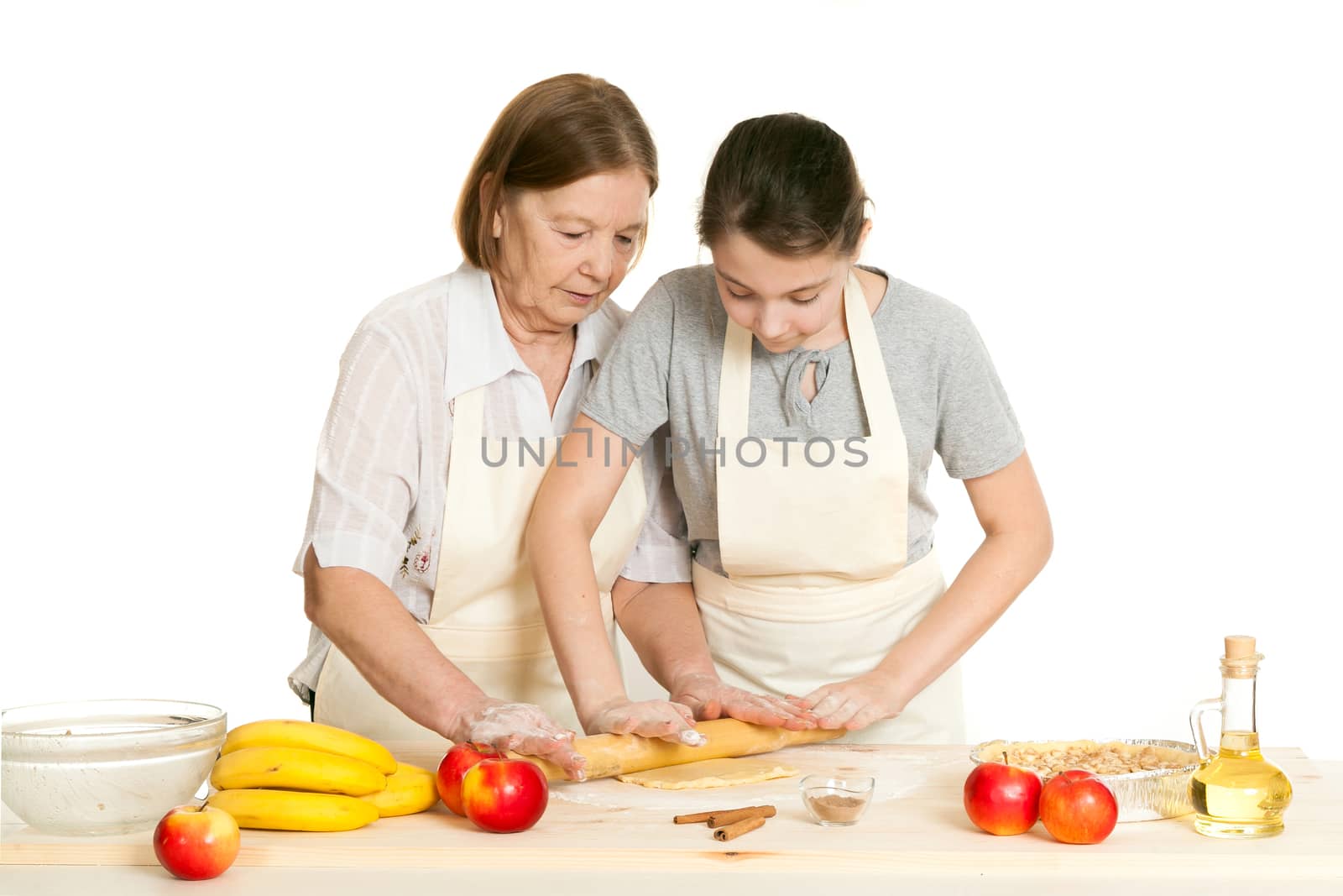 the grandmother and the granddaughter roll dough with a rolling pin for pie on a white background