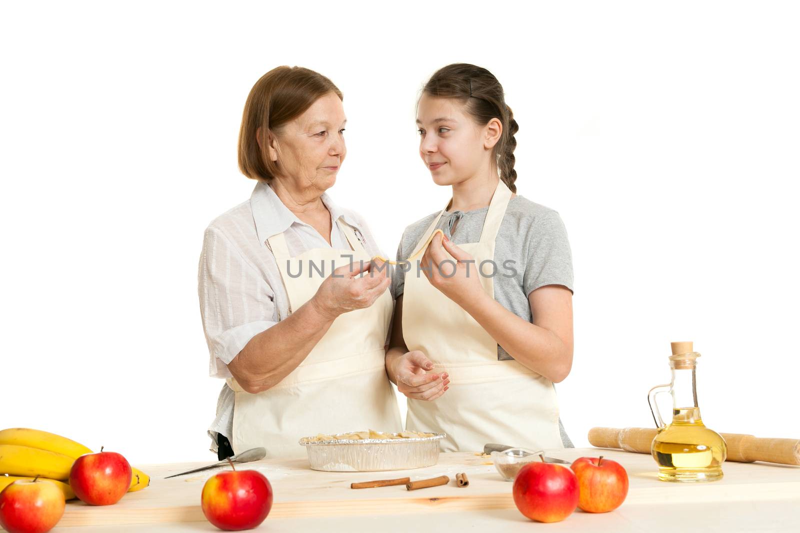 the grandmother and the granddaughter stack dough strips for ornament in a form for pie