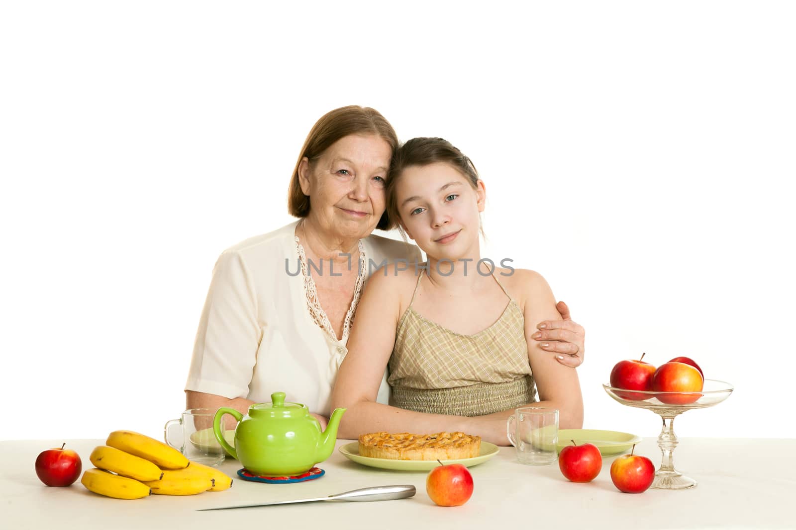 the grandmother and the granddaughter sit at a table with the made pie