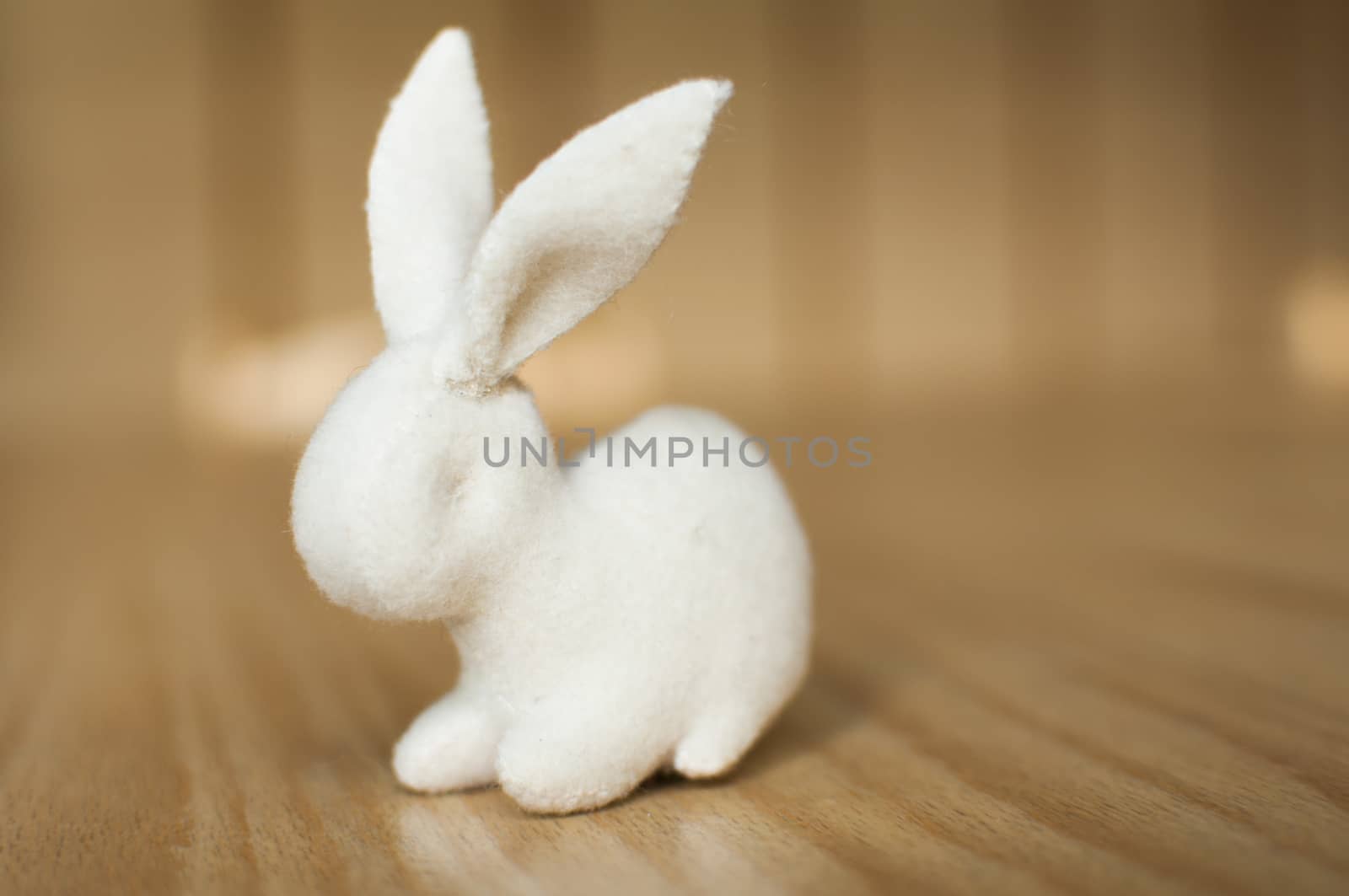 White rabbit on wooden table. Handmade stuffed toy.