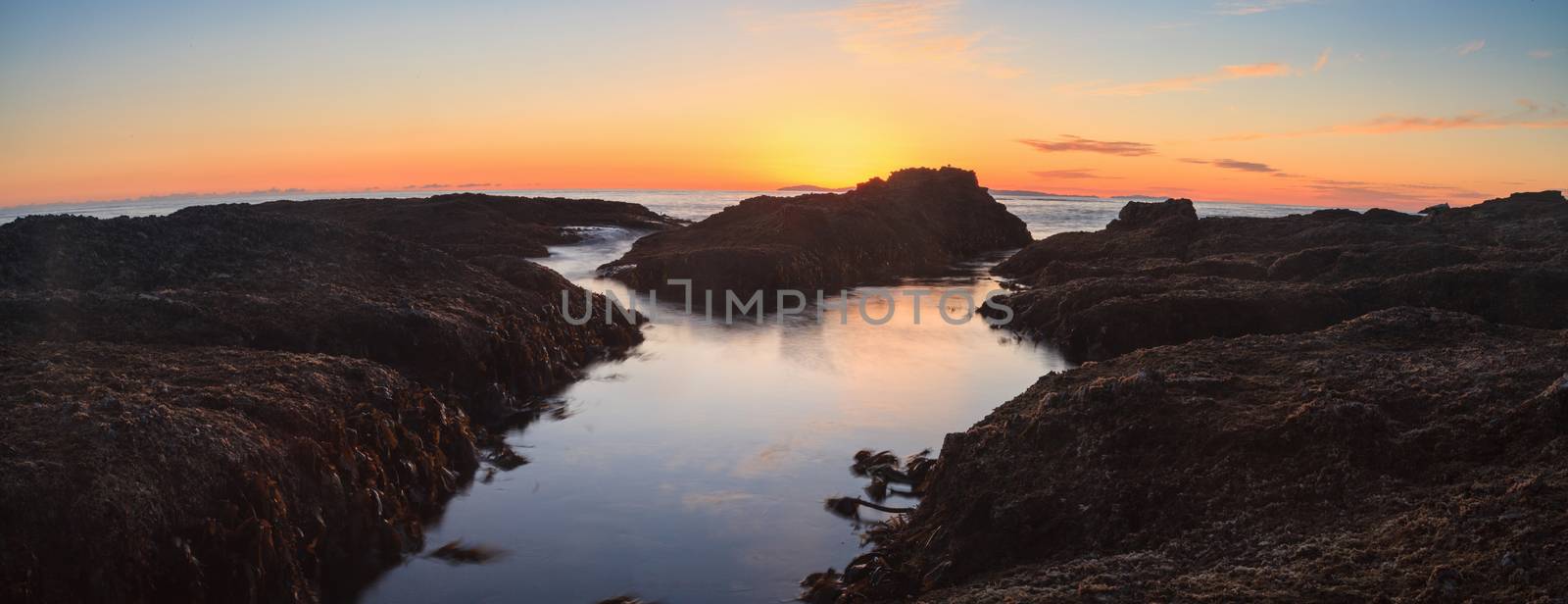 Long exposure of sunset over rocks, giving a mist like effect over ocean in Laguna Beach, California, United States