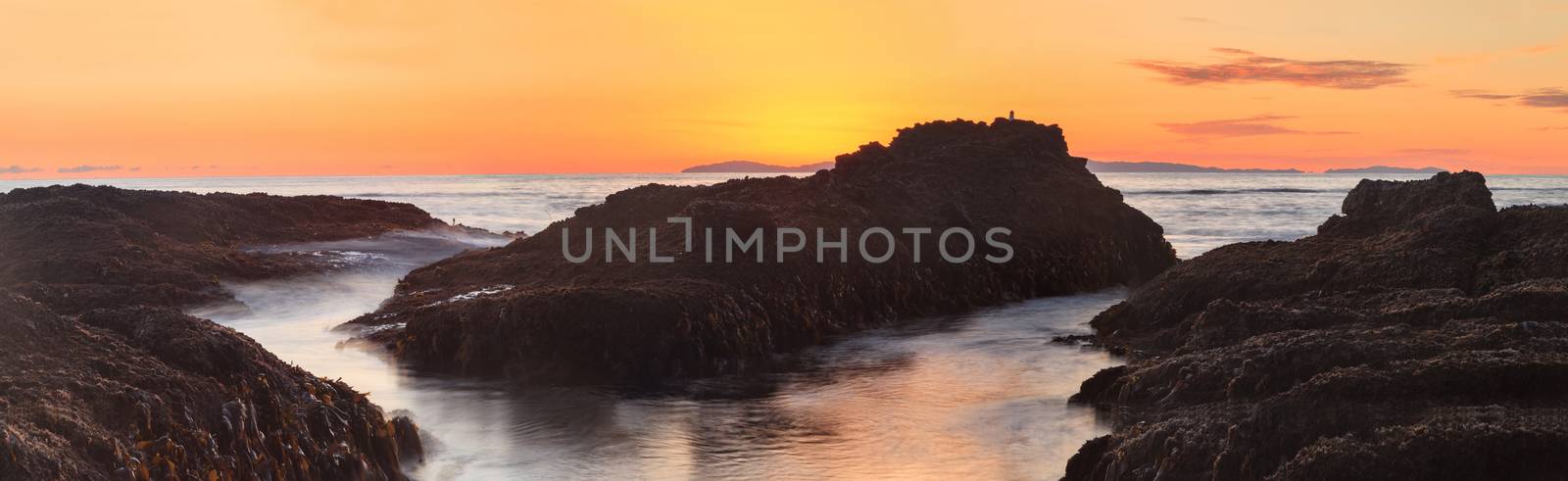 Long exposure of sunset over rocks, giving a mist like effect over ocean in Laguna Beach, California, United States