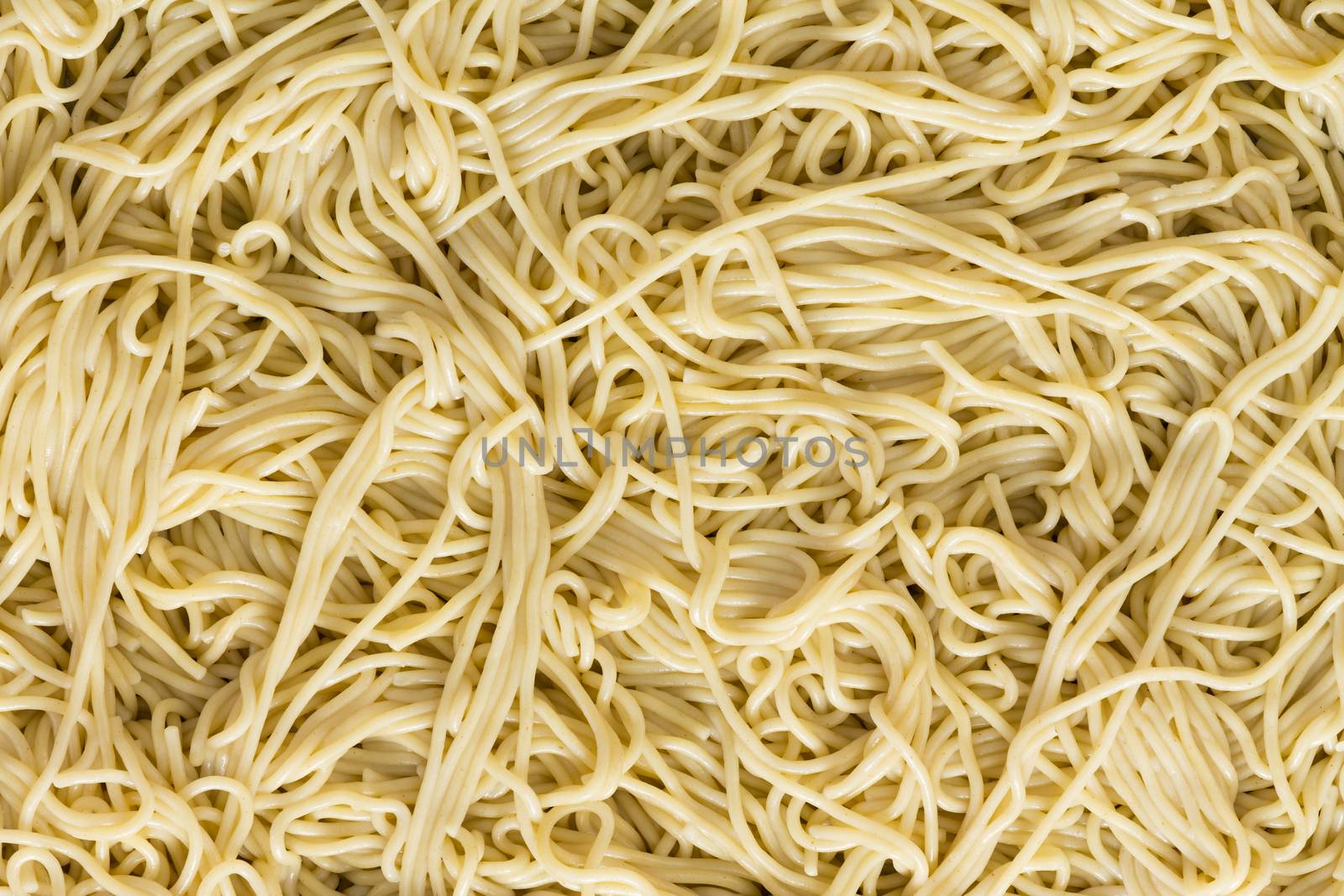 Italian spaghetti pasta background texture with a jumbled pattern of cooked plain noodles viewed full frame close up from overhead