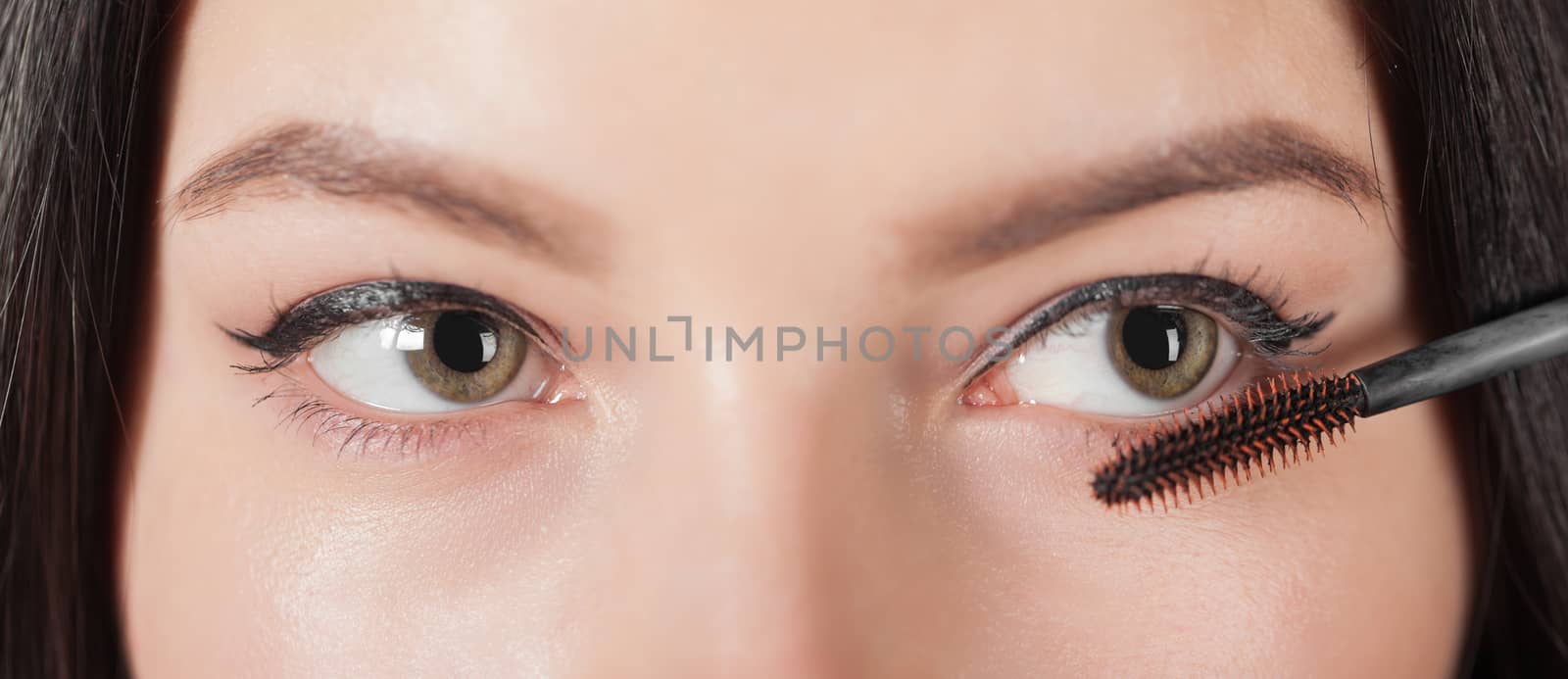 woman paints the eyelashes mascara, eye closeup