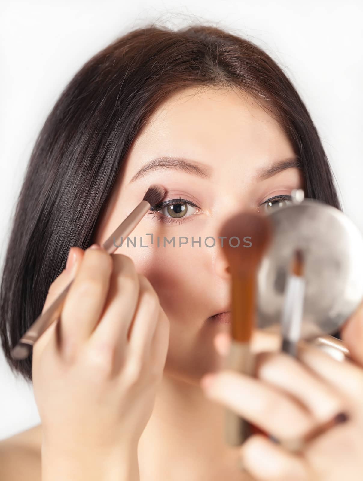 the girl does make-up on a light background