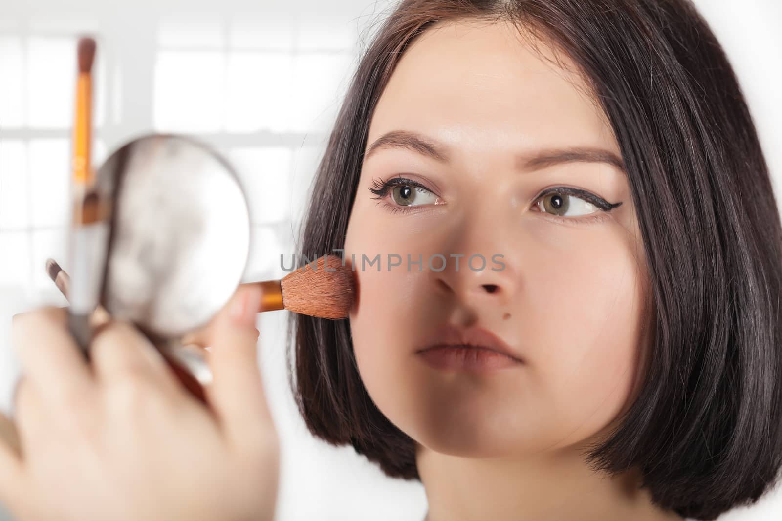 the girl does make-up on a light background