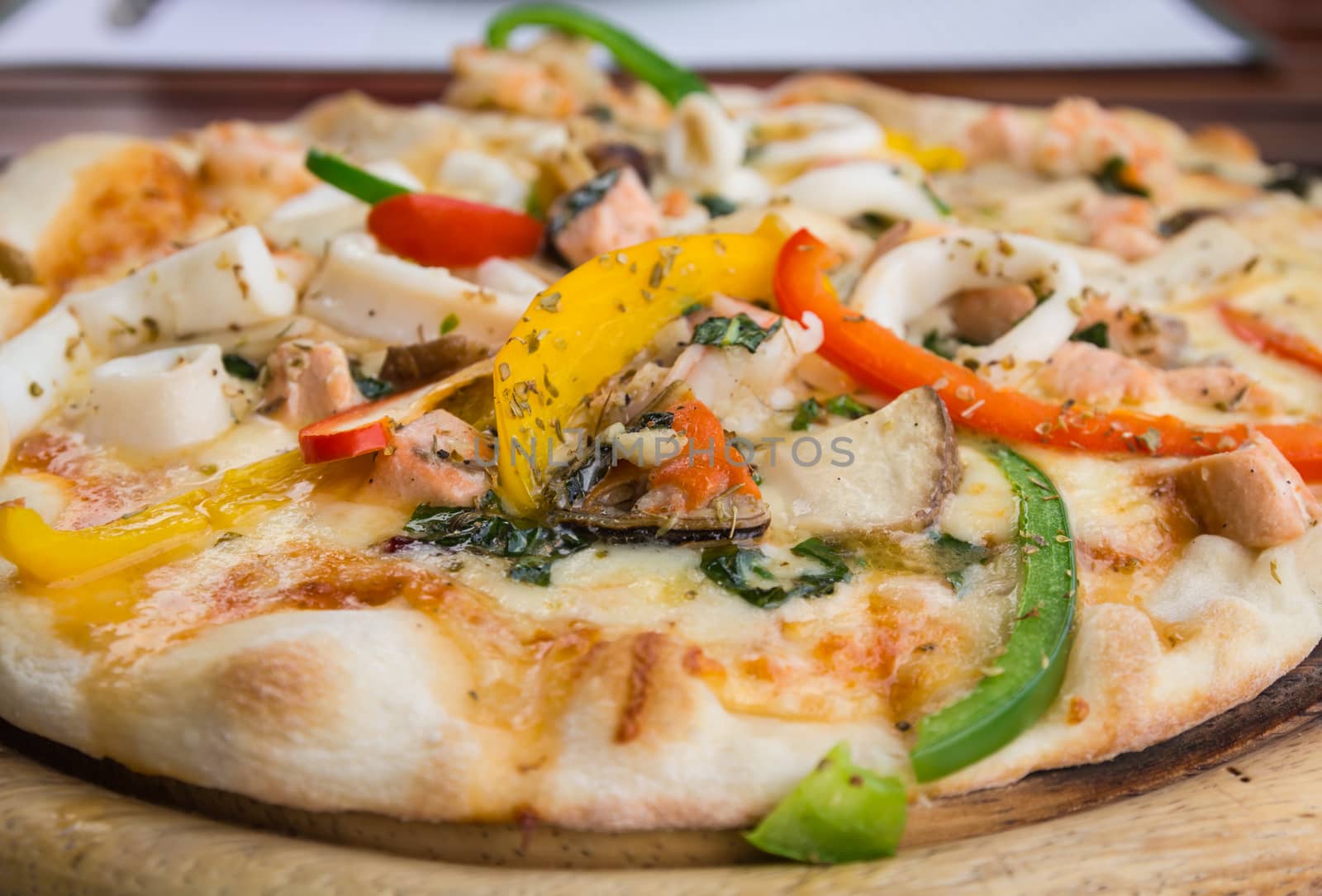 Closeup delicious pizza with seafood on wooden stand.