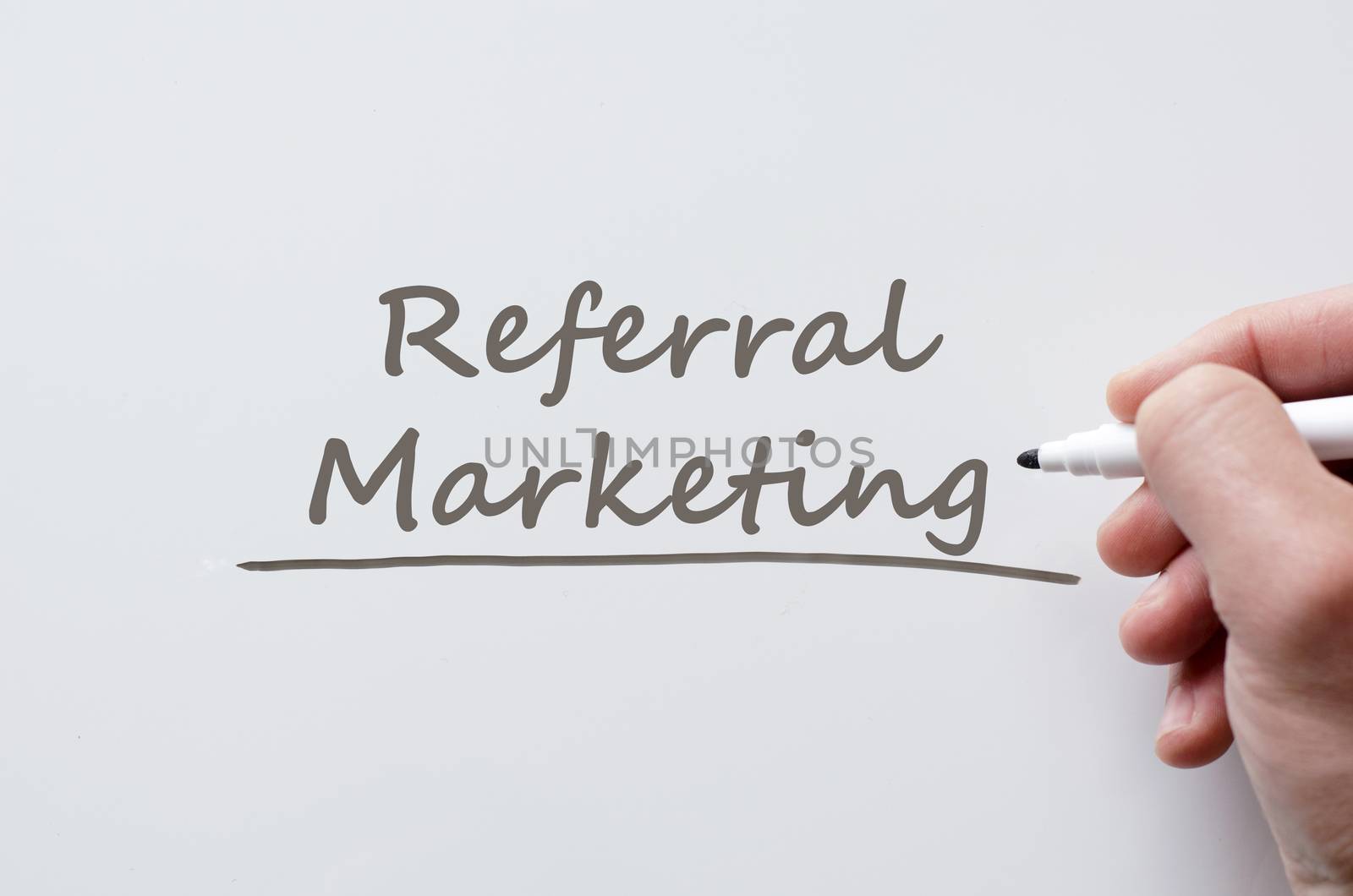 Human hand writing referral marketing on whiteboard