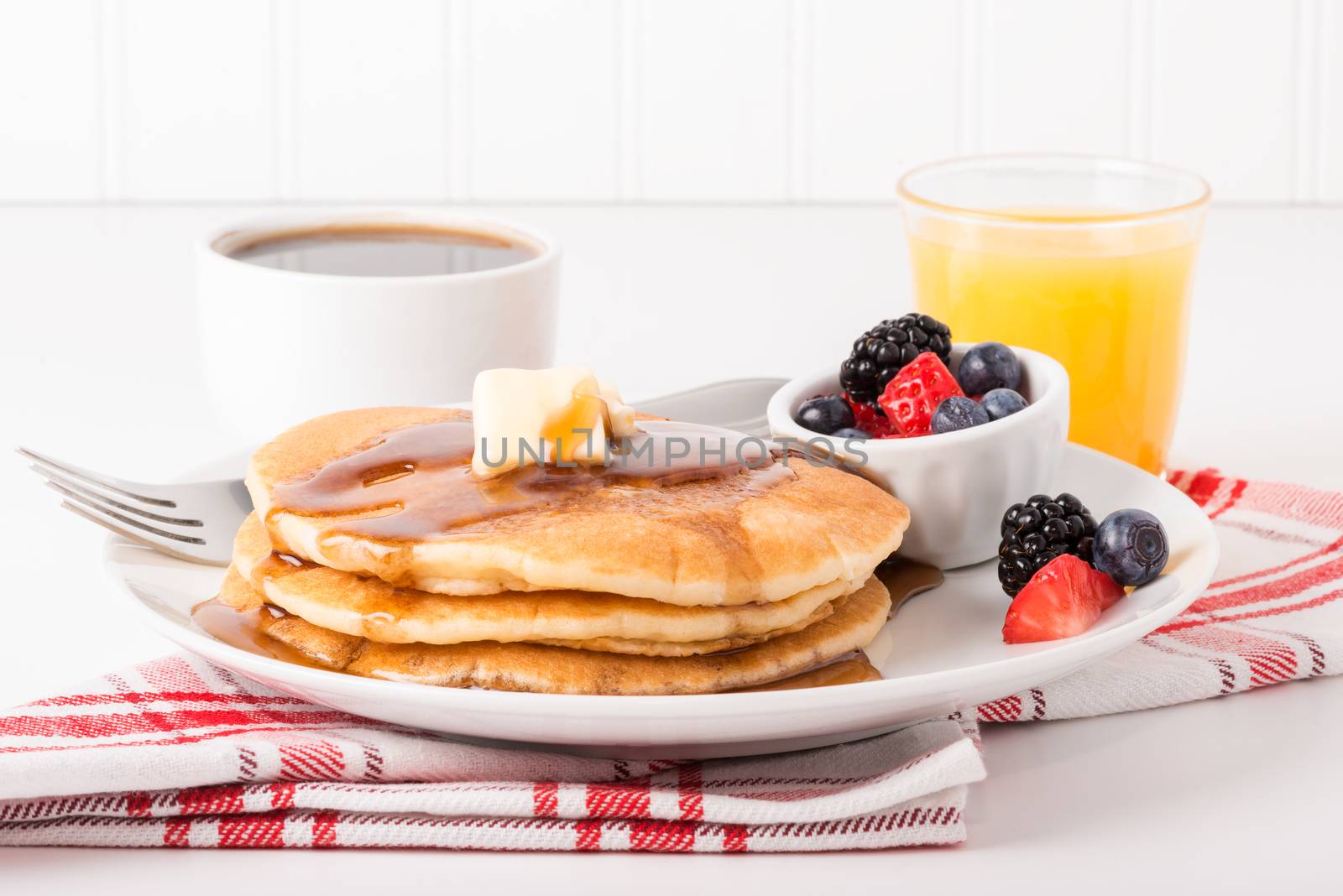 Pancakes and maple syrup with coffee and orange juice.