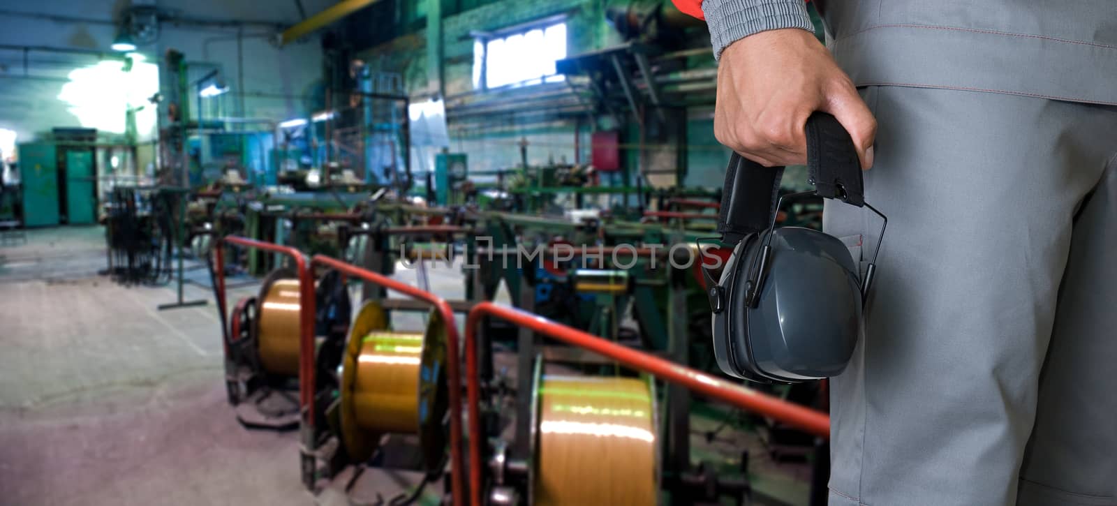 Worker with protective headphone at man hands at industrial factory