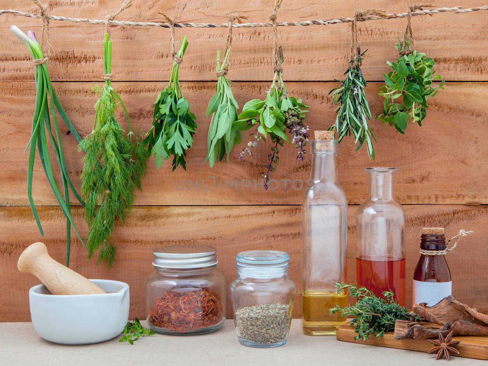 Assorted hanging herbs ,parsley ,oregano,sage,rosemary,sweet basil,dill,spring onion  and  set up with dry and fresh thyme ,olive oil ,sesame oil ,cinnamon and star anise  for seasoning concept on rustic old wooden background.