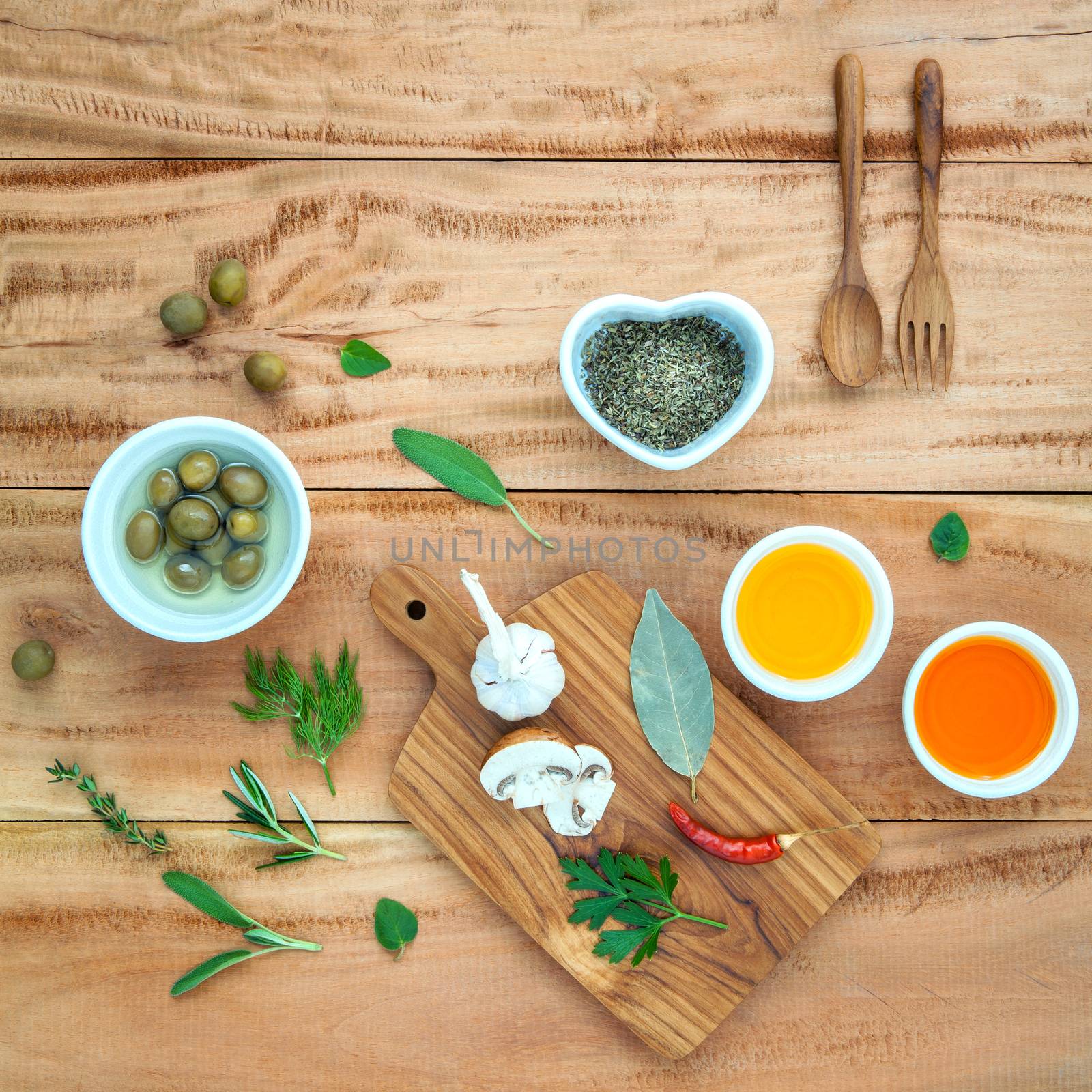 Different sorts of cooking oil,olive oil flavored and Sesame oil with  spices herbs rosemary ,thyme,dill,sage mint and parsley and wooden spoon set up with wooden background concept for international cuisine.